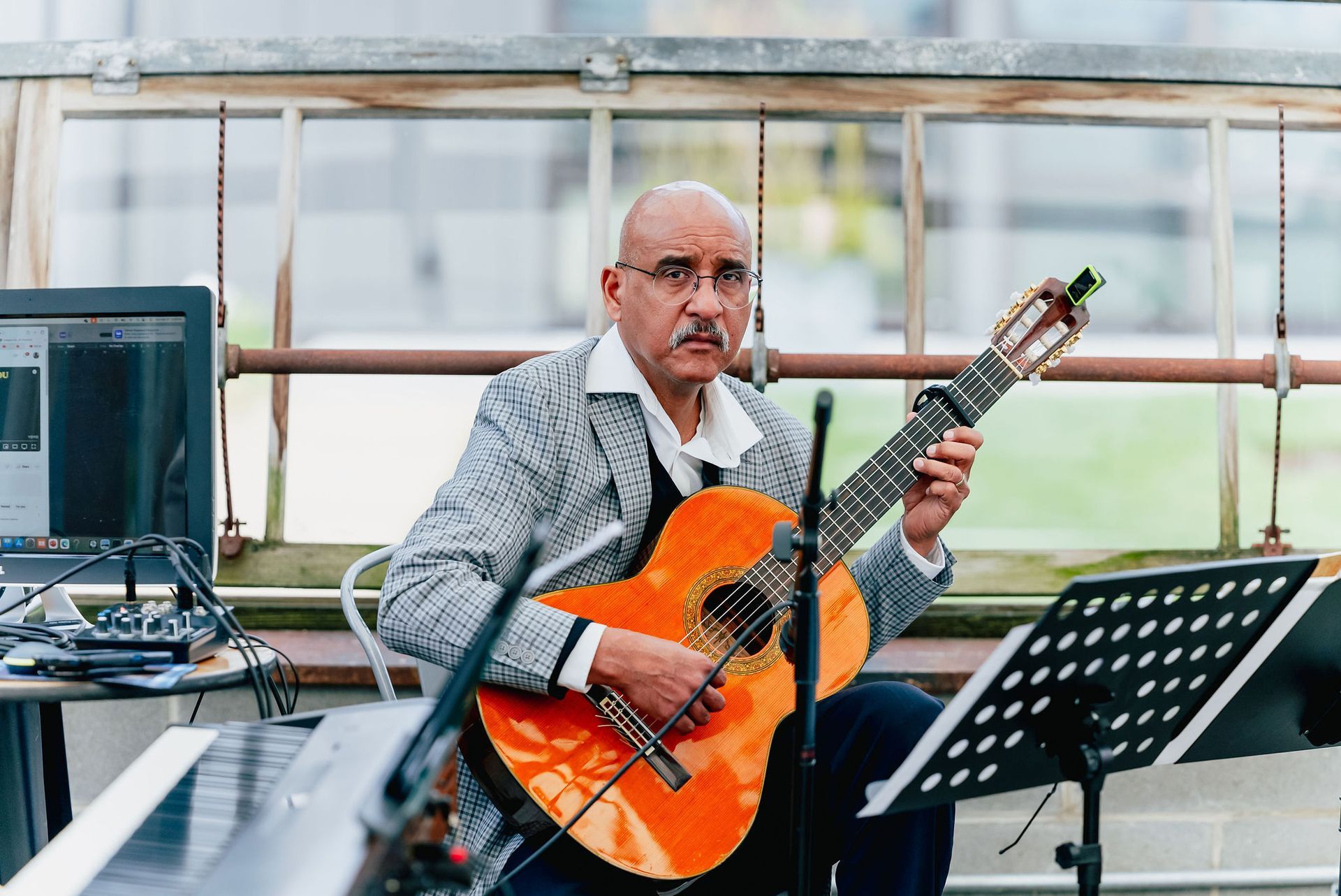 A man is playing a guitar in front of a piano.