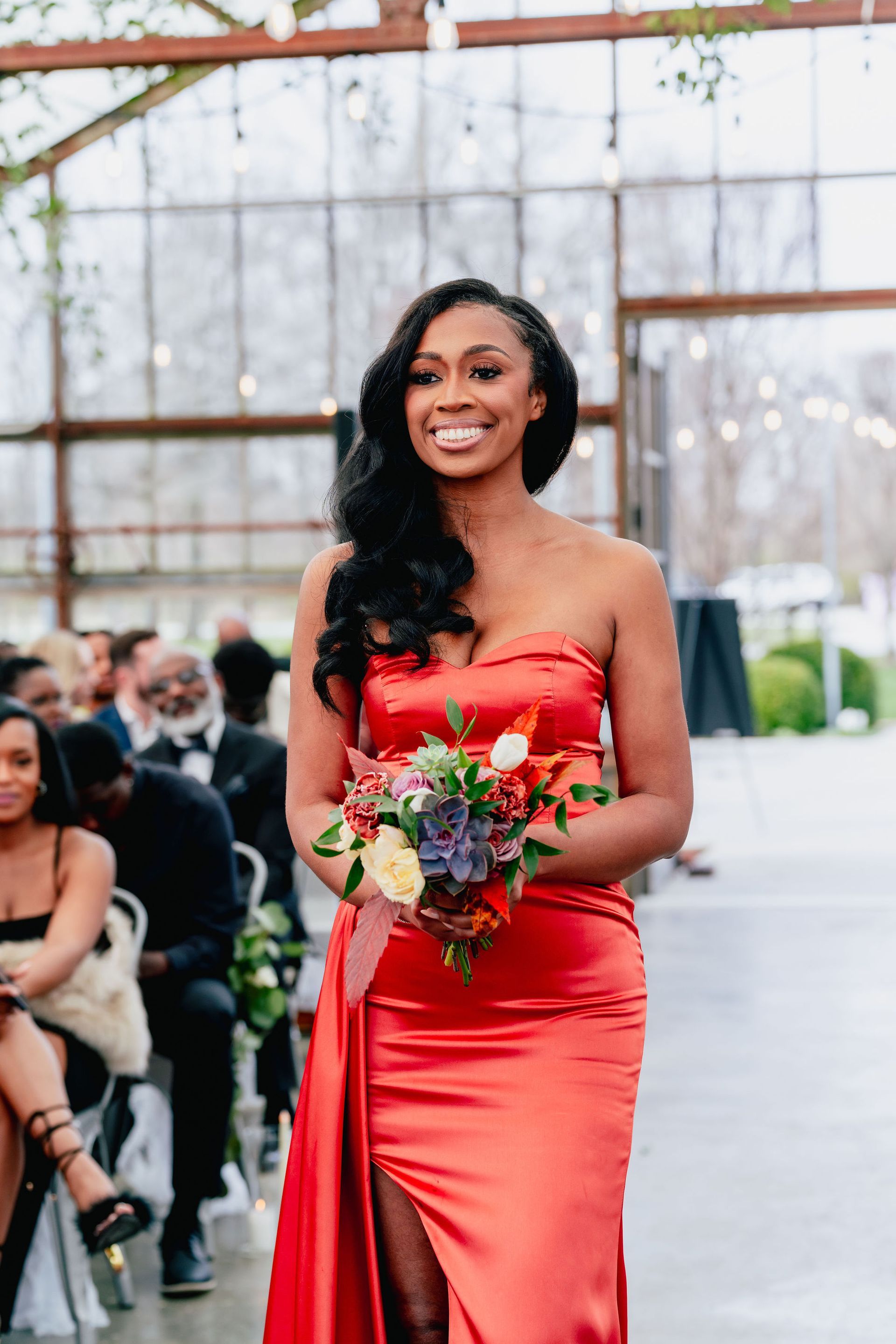 A woman in a red dress is walking down the aisle at a wedding.