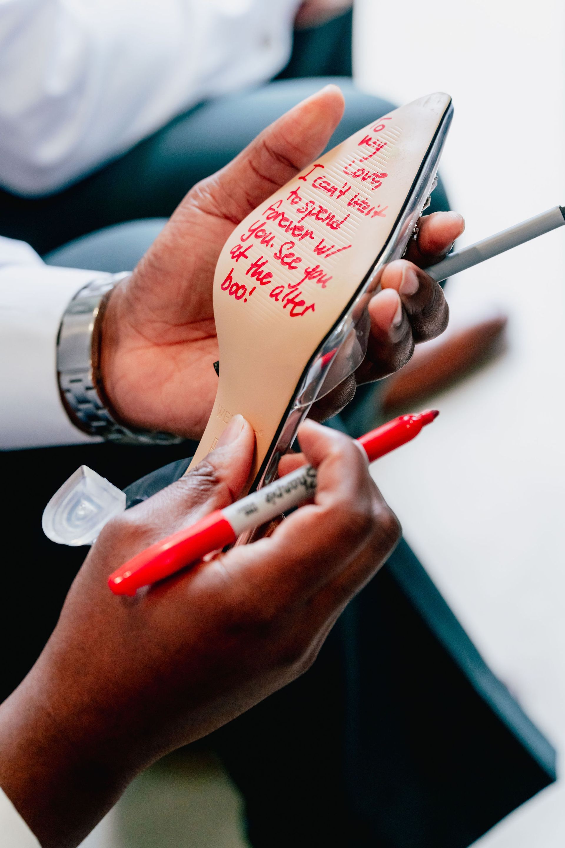 A person is writing on the sole of a shoe with a marker.
