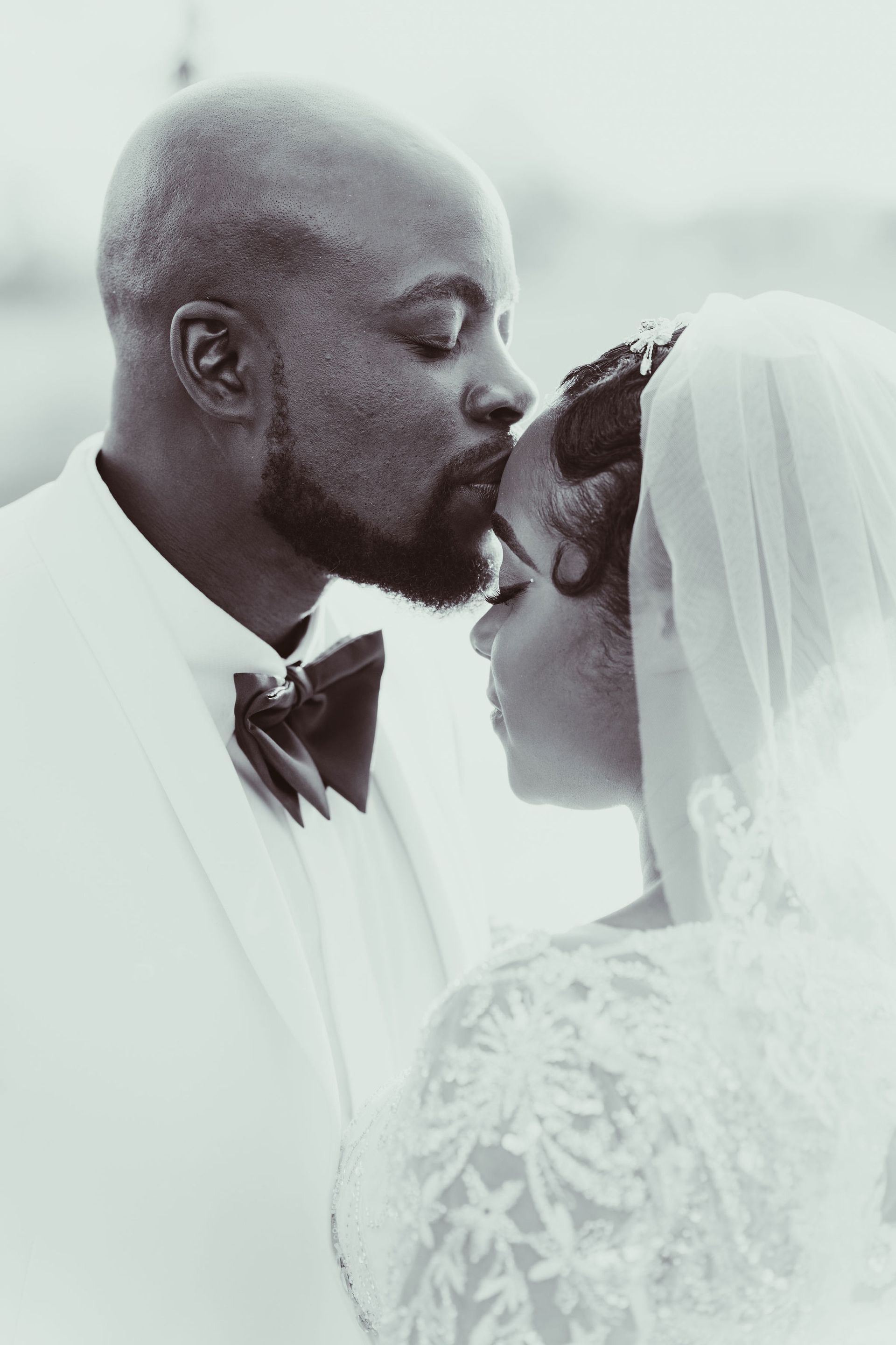 A bride and groom are kissing in a black and white photo.