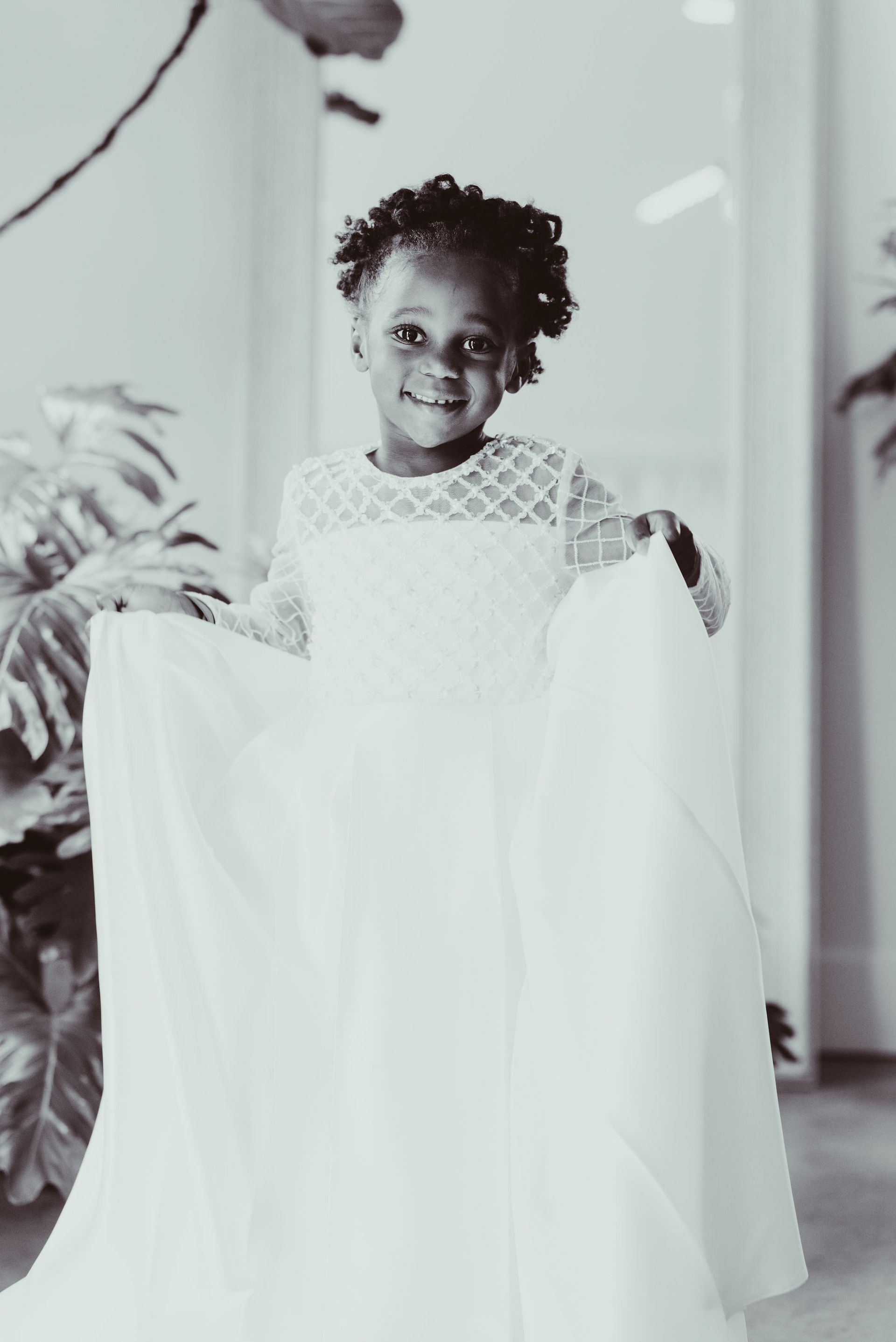 A little girl in a white dress is holding a white cloth.