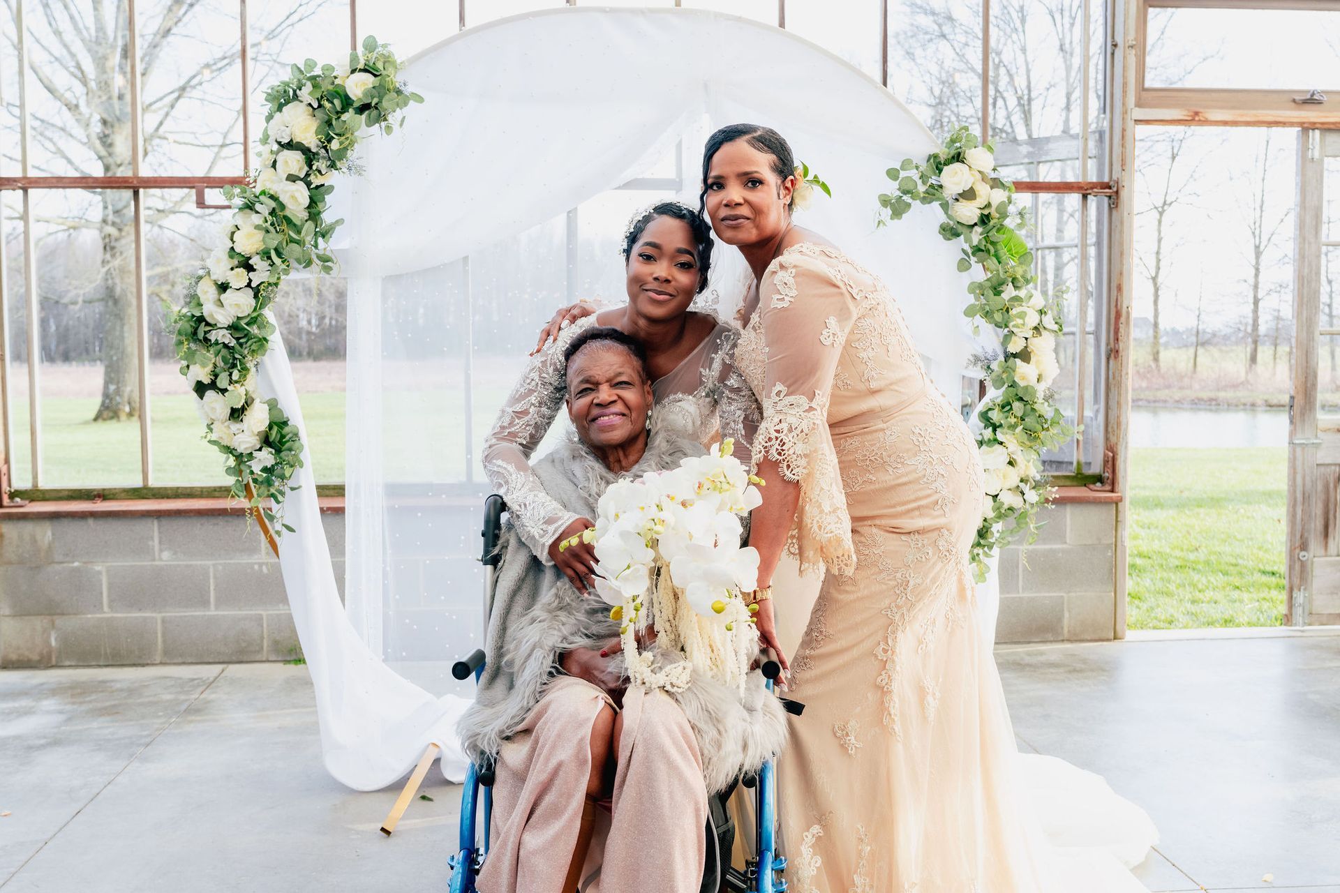 A bride and her bridesmaids are posing for a picture with a woman in a wheelchair.