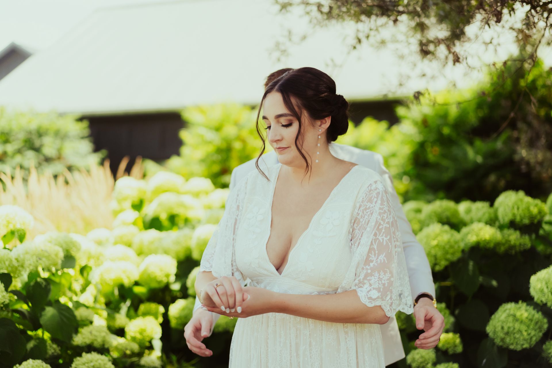 A bride in a white dress is standing next to a groom in a garden at Jorgensen Farms Oak Grove.