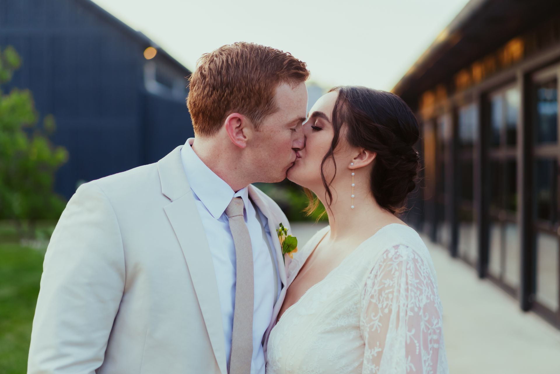 A bride and groom are kissing in front of a building at Jorgensen Oak Grove