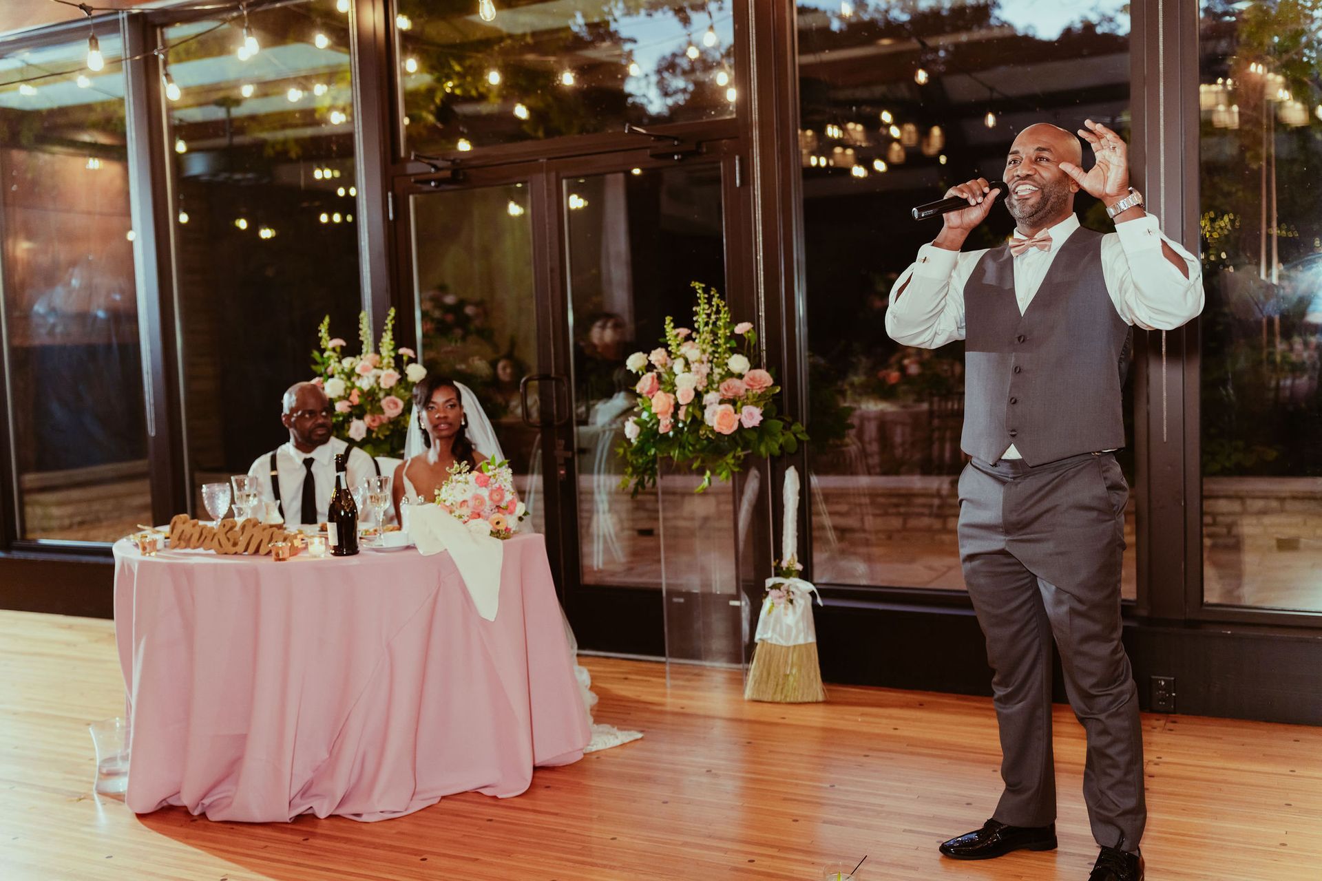 A man is singing into a microphone at a wedding reception.