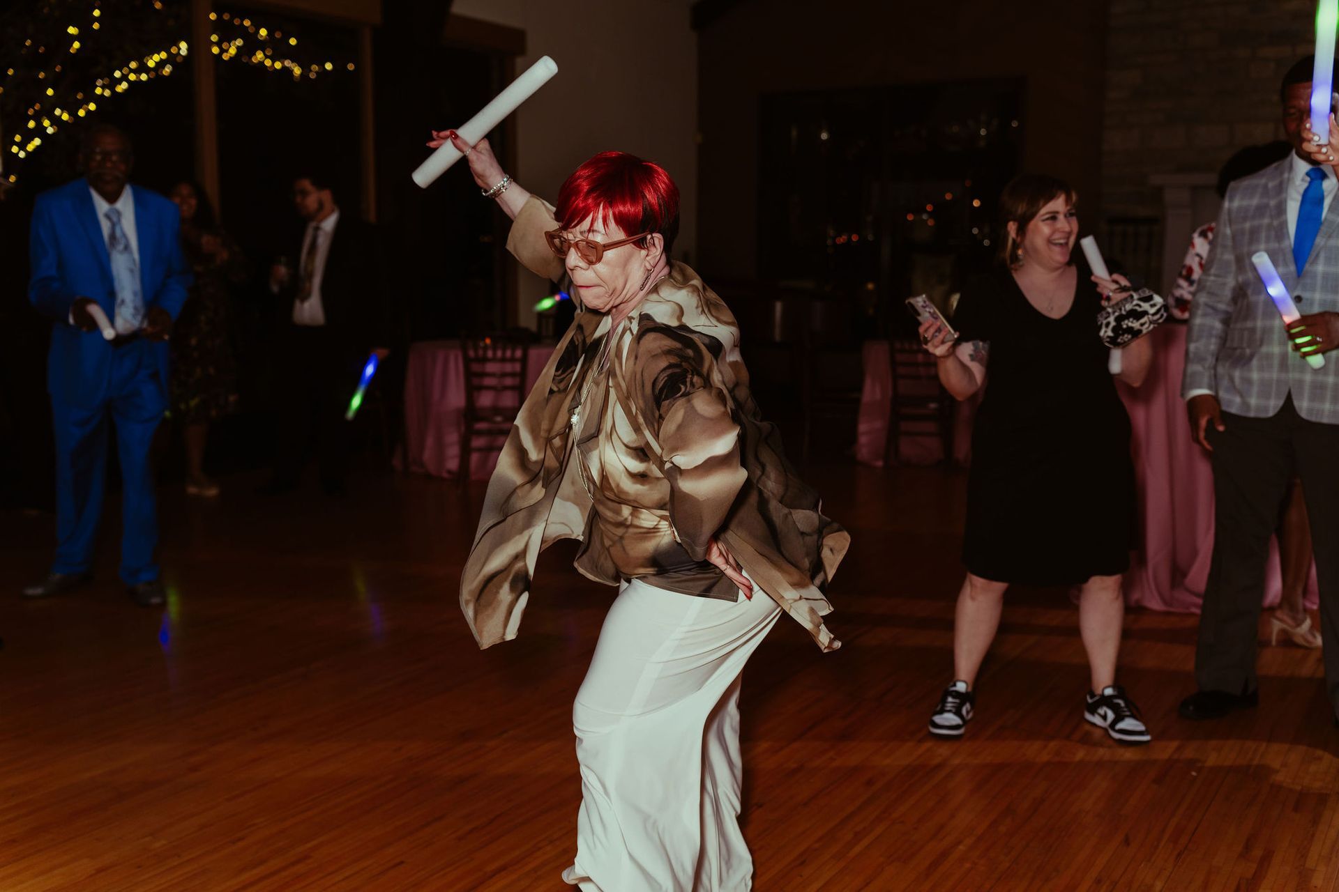 A woman is dancing on a dance floor with glow in the dark sticks.
