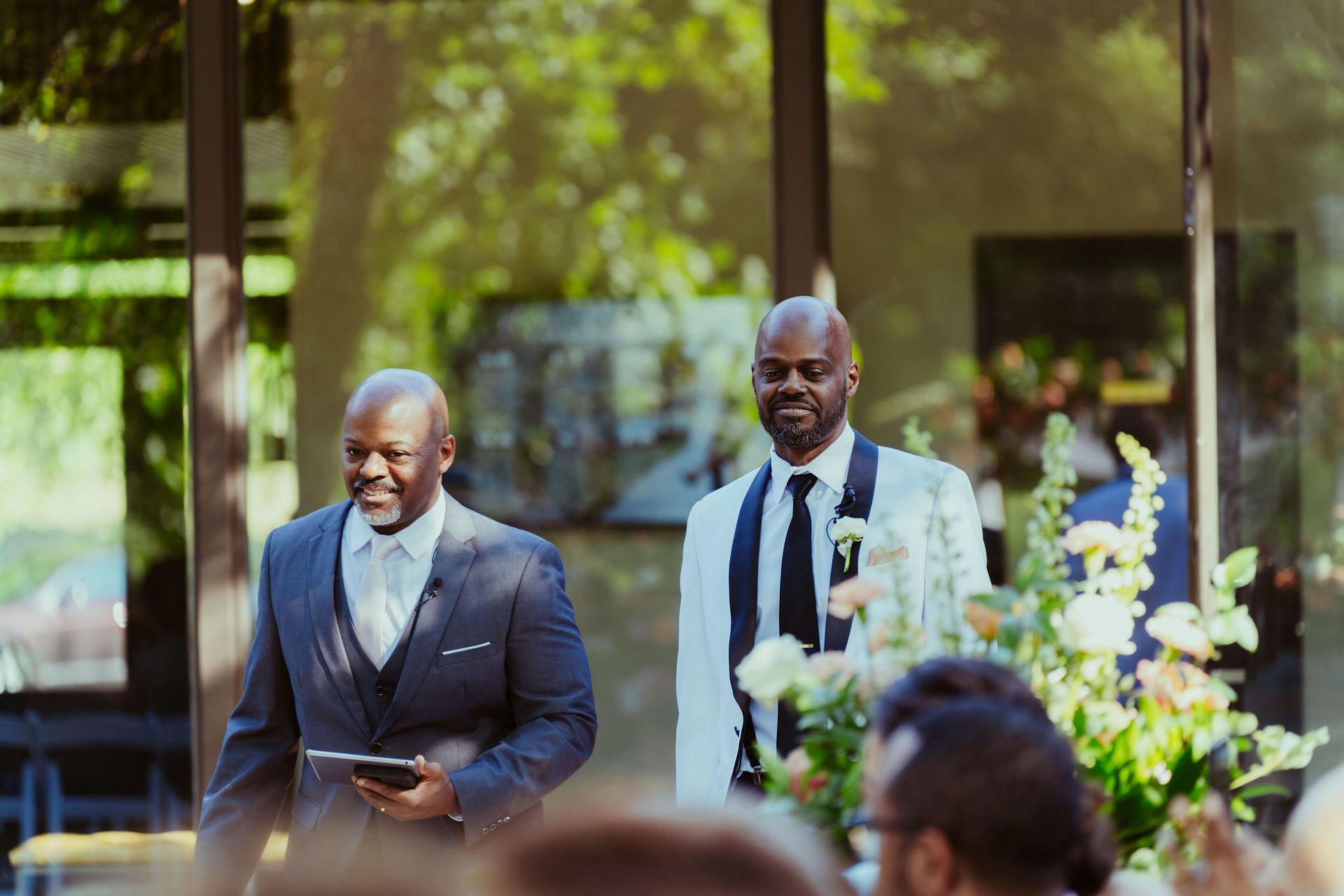Two men are standing next to each other at a wedding ceremony.