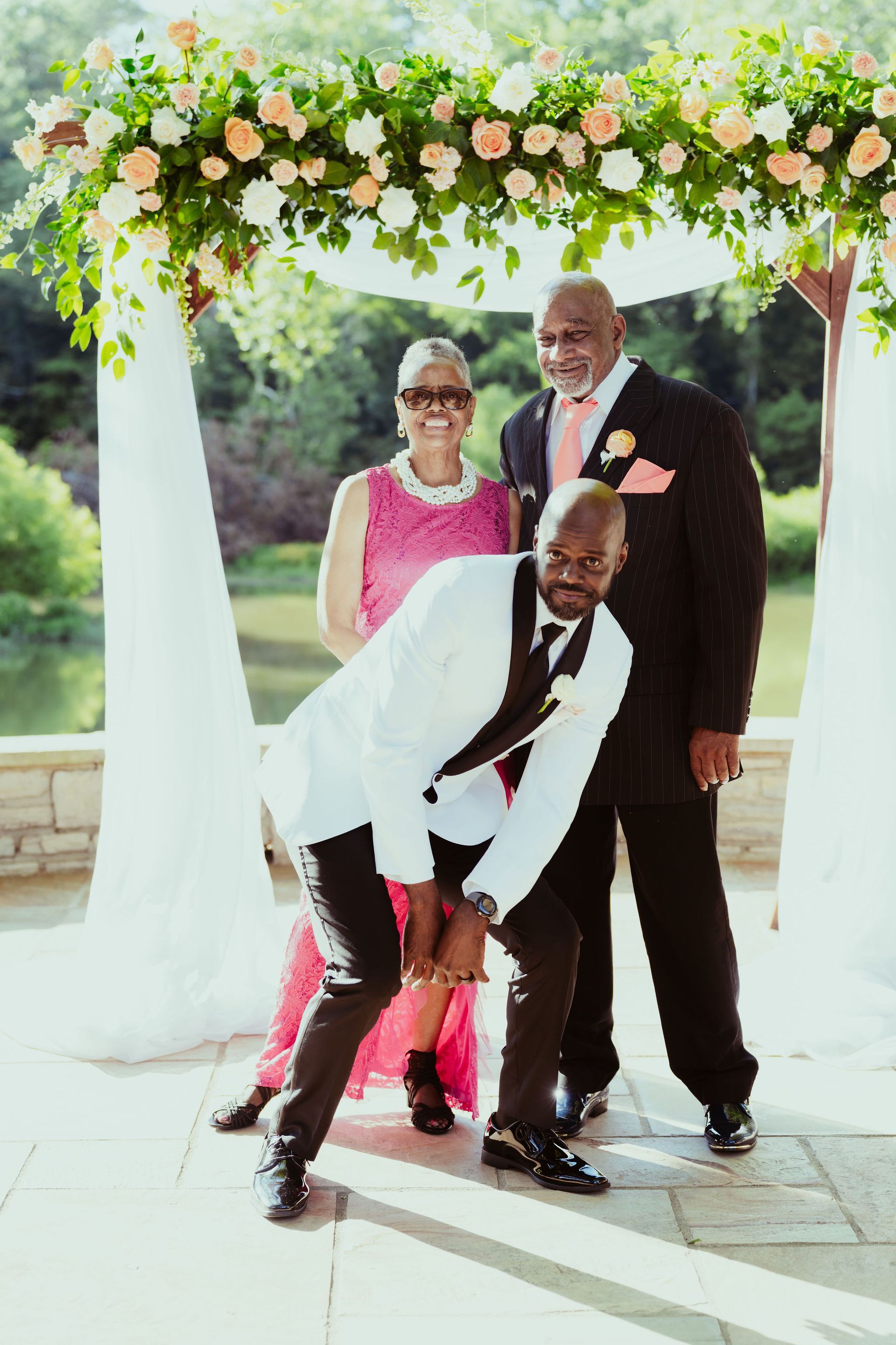 A man in a tuxedo is posing for a picture with his family at a wedding.