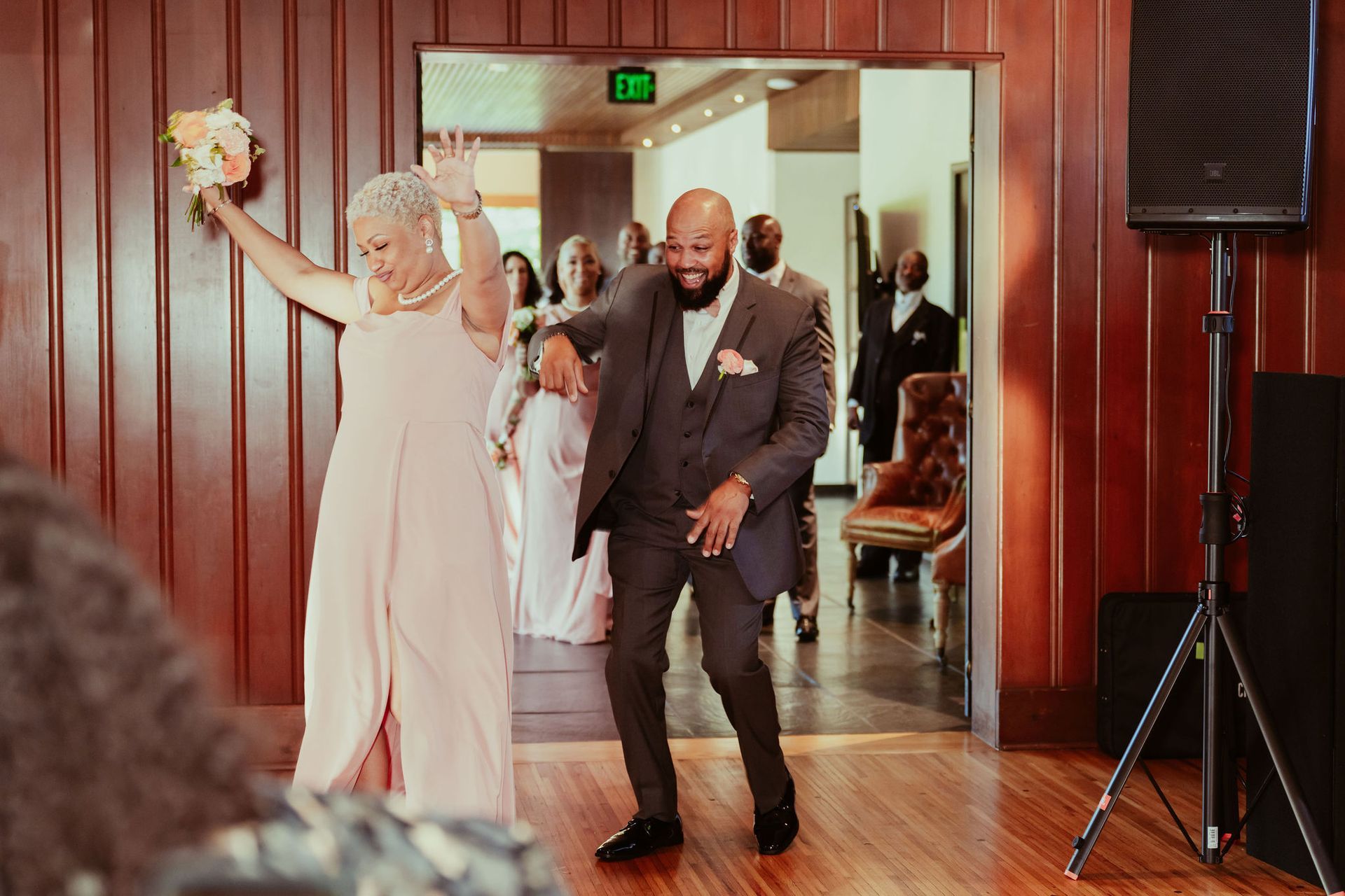 A bride and groom are walking into a room at their wedding reception.