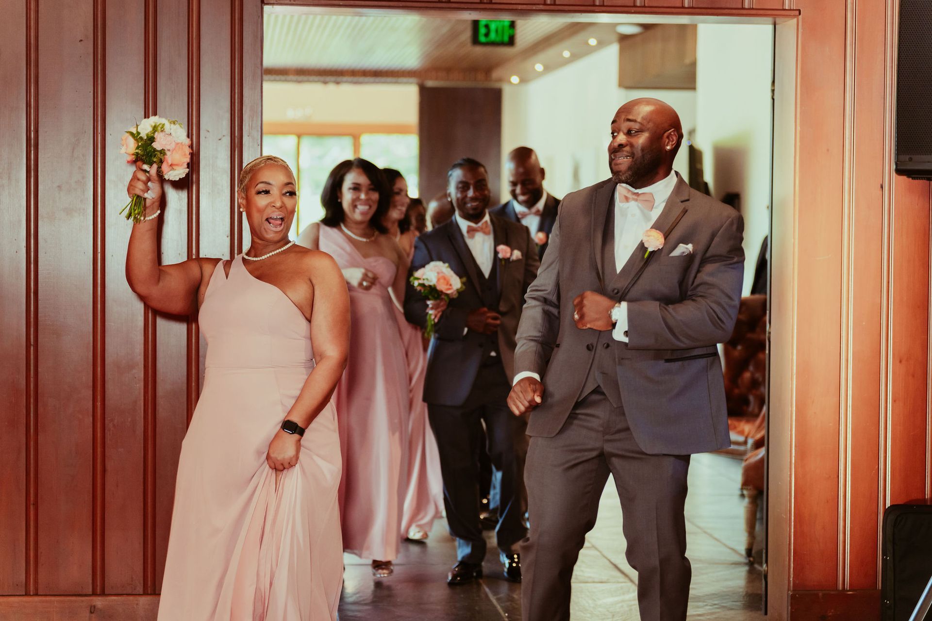 A bride and groom are walking through a doorway with their wedding party.