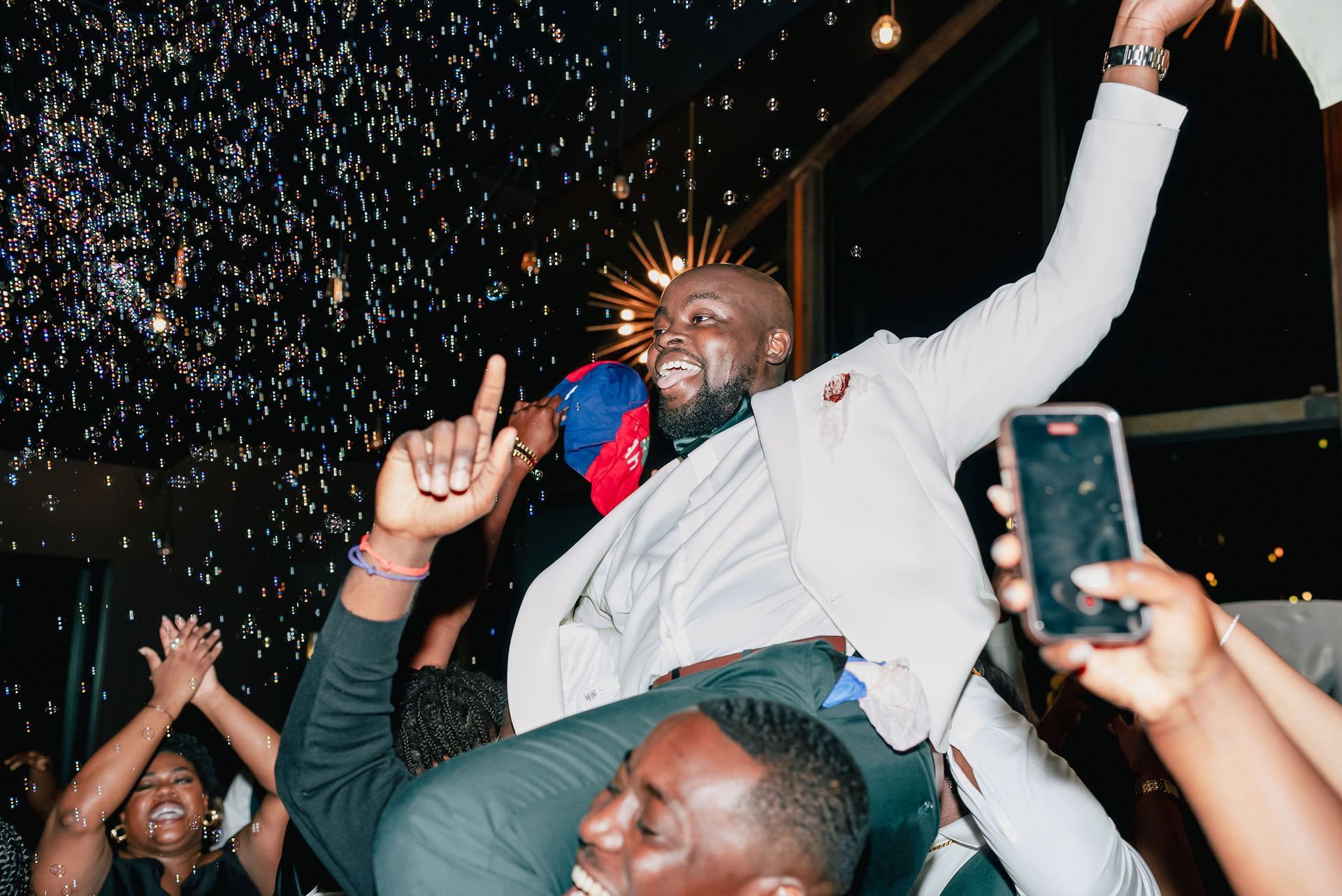 A man is being carried in the air by a group of people at a party.