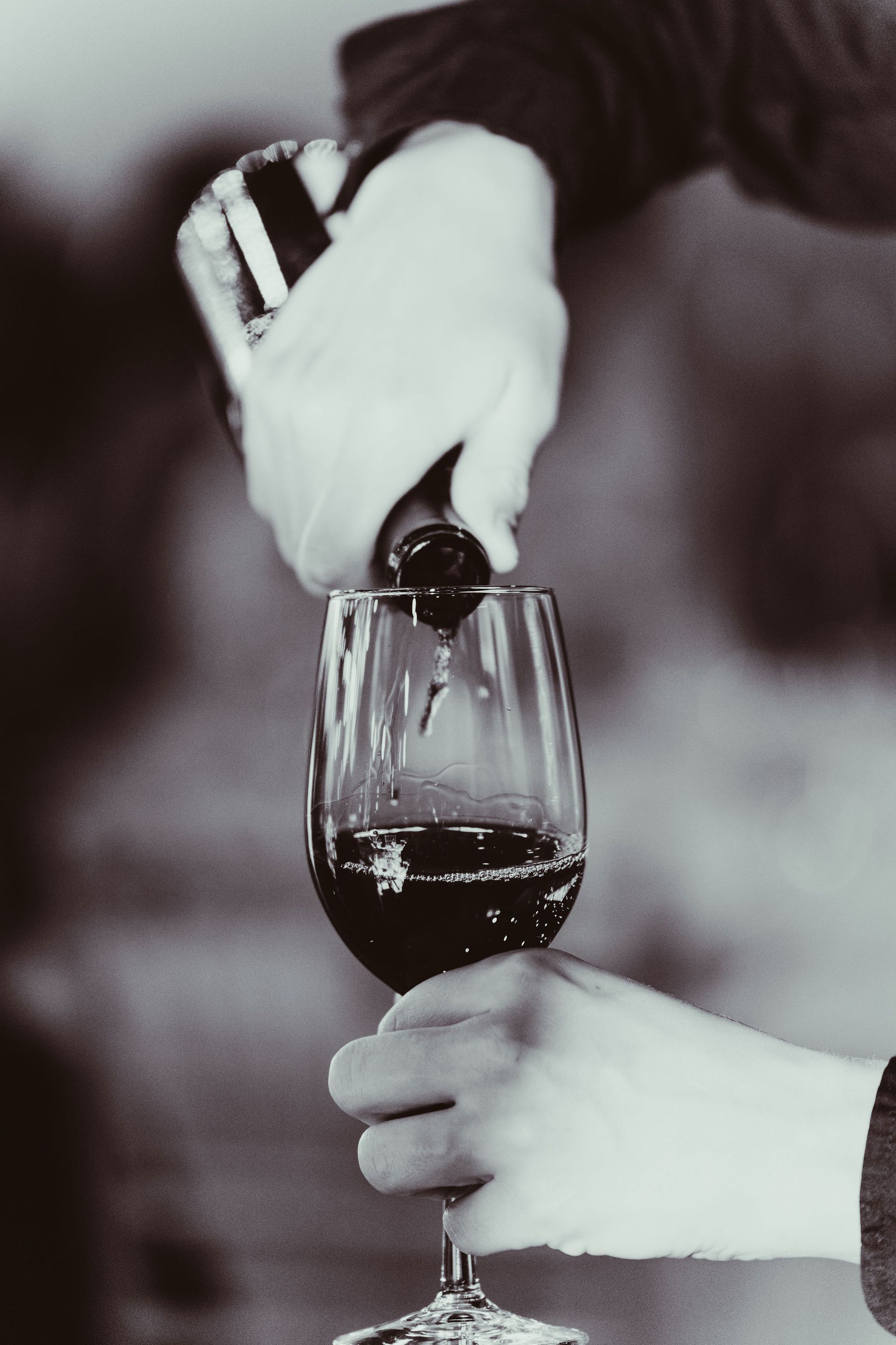 A person is pouring red wine into a glass