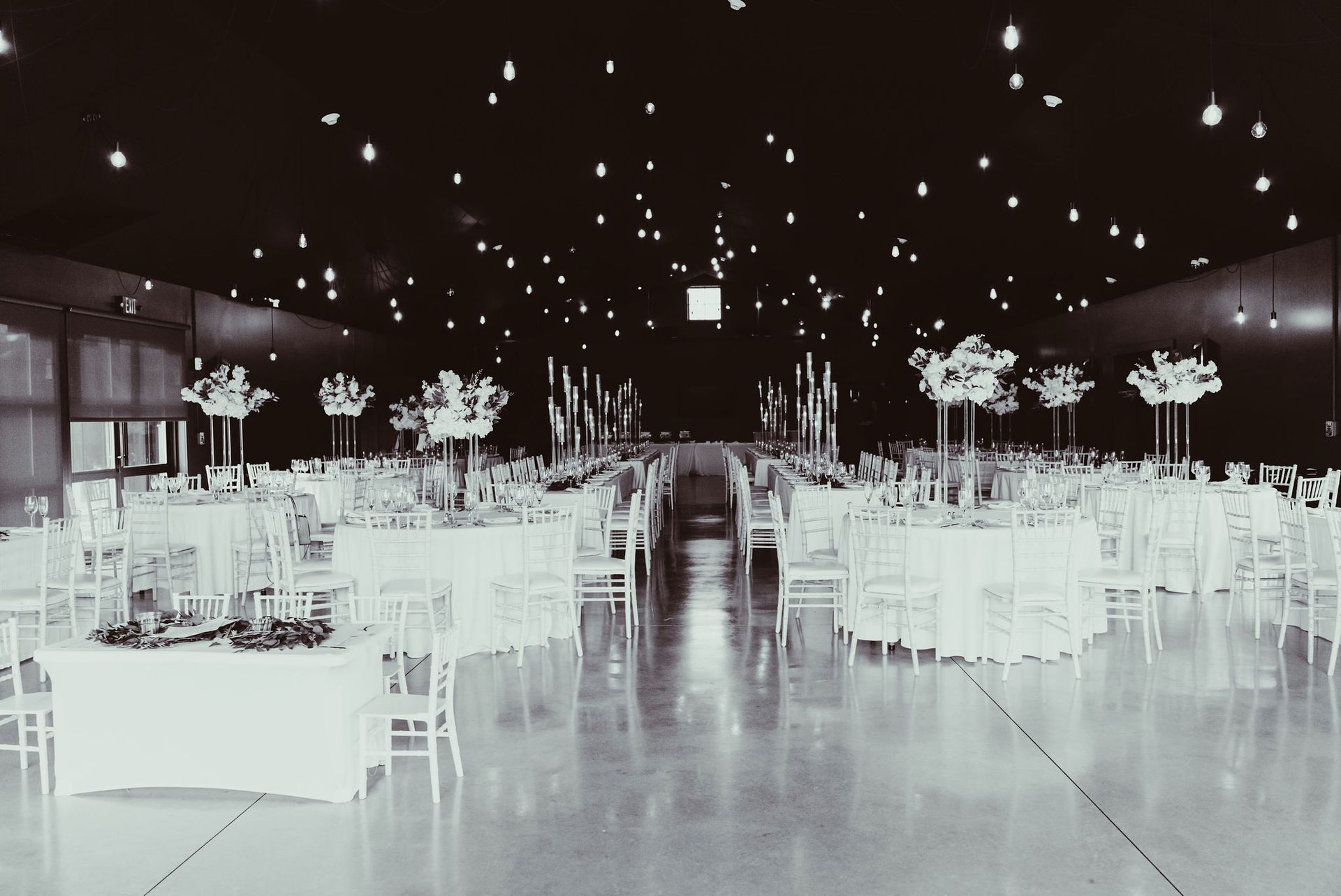 A large room with tables and chairs set up for a wedding reception