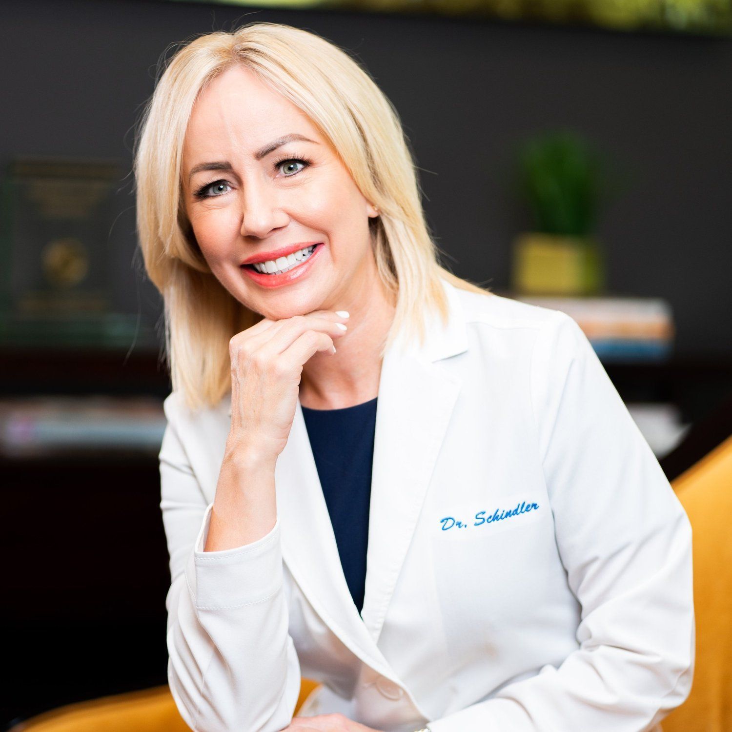 a woman in a white lab coat is smiling for the camera .