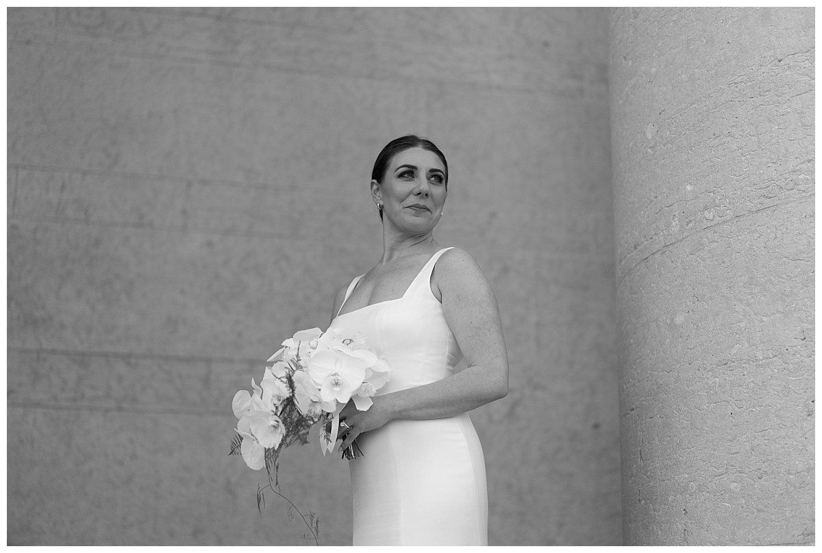 a black and white photo of a woman in a wedding dress holding a bouquet of flowers .