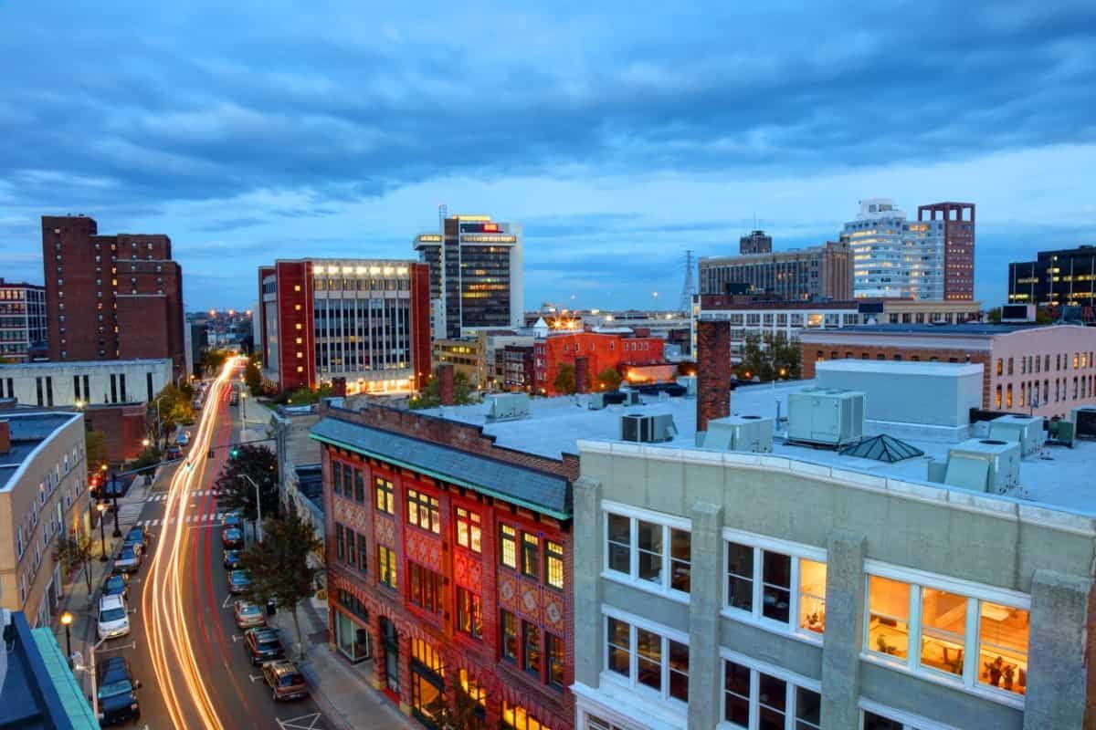Downtown cityscape at dusk with illuminated buildings and light trails on the street