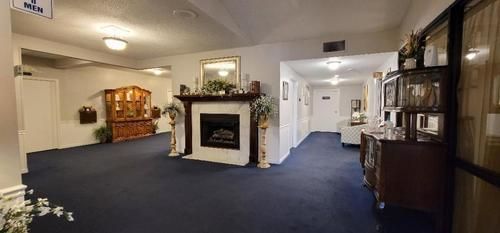 Spacious lobby with blue carpet, fireplace, and hallway seating area under warm lighting