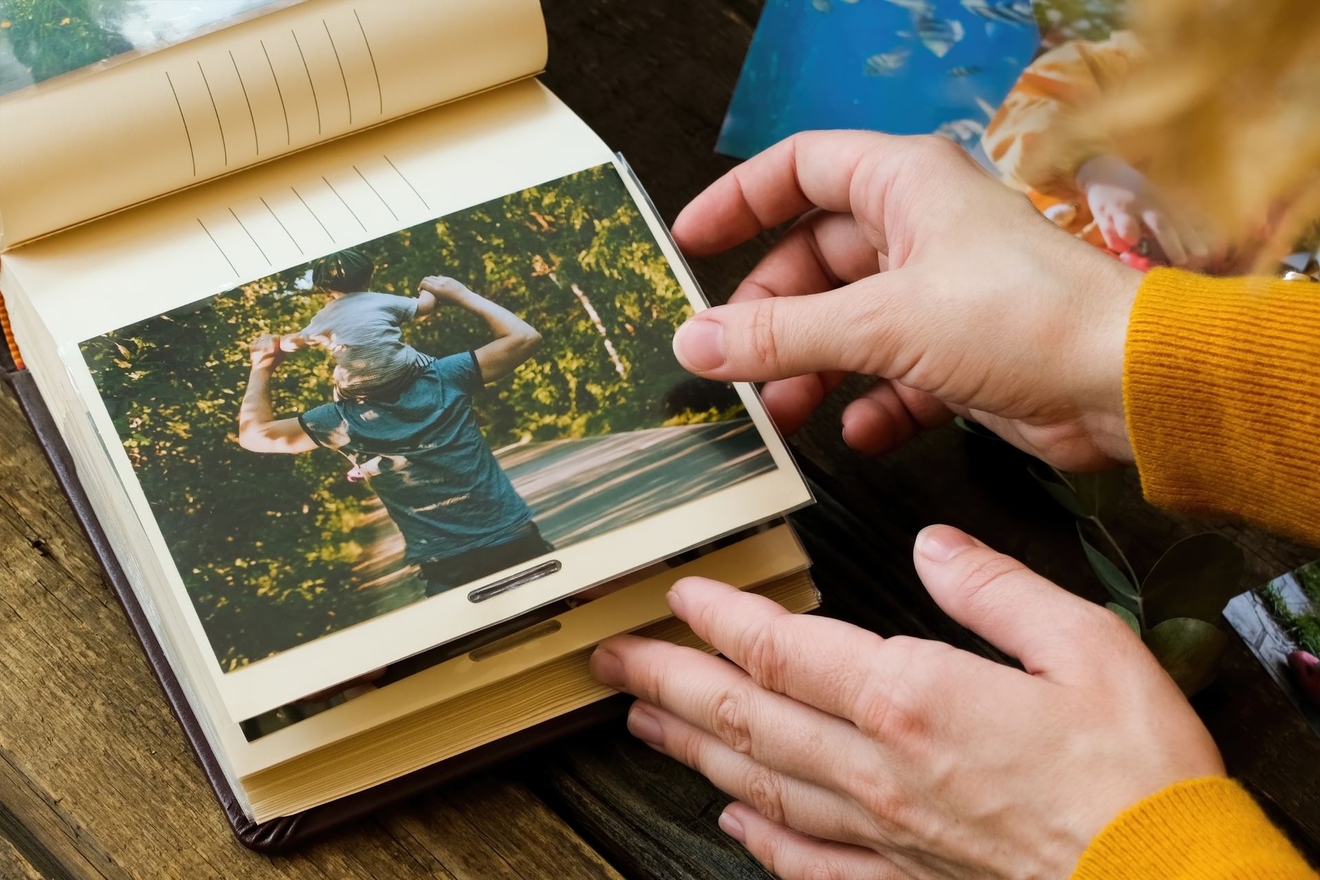 Hands turning a photo album page with a snapshot of a person outdoors in a blue shirt