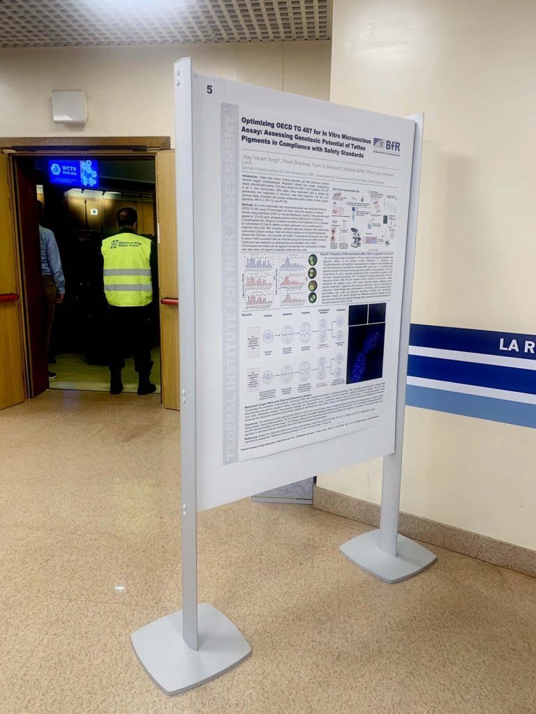 Un cartellone pubblicitario è esposto in un corridoio, con un agente di sicurezza a una porta aperta nelle vicinanze.