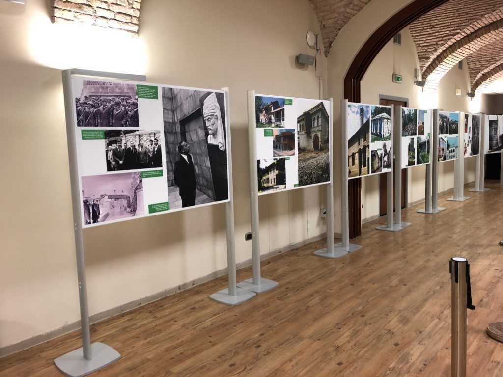 Pannelli espositivi fotografici in un corridoio della galleria con soffitti a volta e pavimenti in legno.