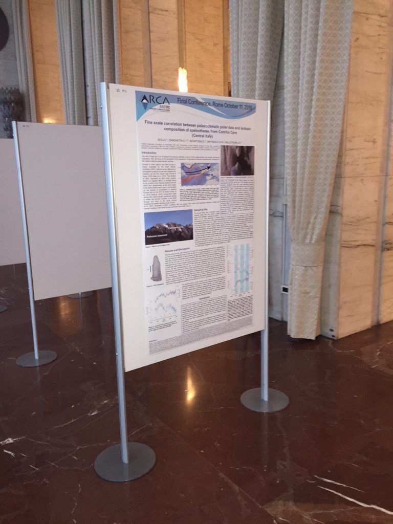 Esposizione di poster in un museo o in una galleria, con pannelli informativi su supporti, tende e pavimento lucido.