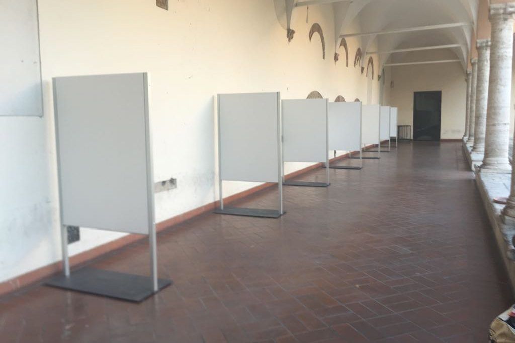 Corridoio vuoto del museo con una fila di pannelli divisori grigi su un pavimento piastrellato.