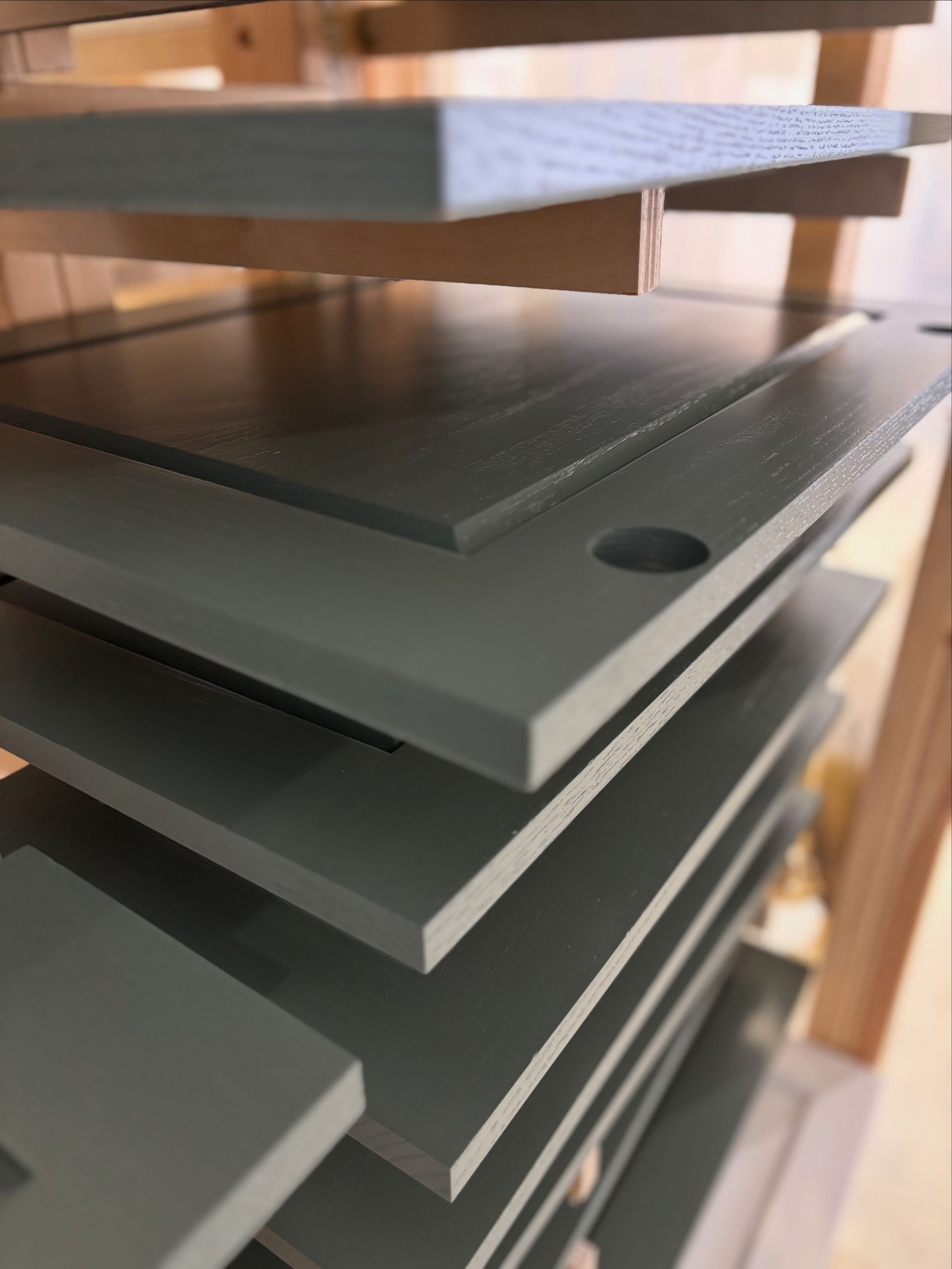 Gray cabinet doors drying on a wooden rack after being painted.