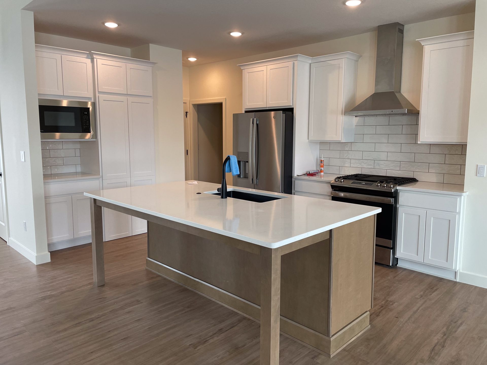 Modern kitchen with white cabinets, stainless steel appliances, and large island with a light wooden base.