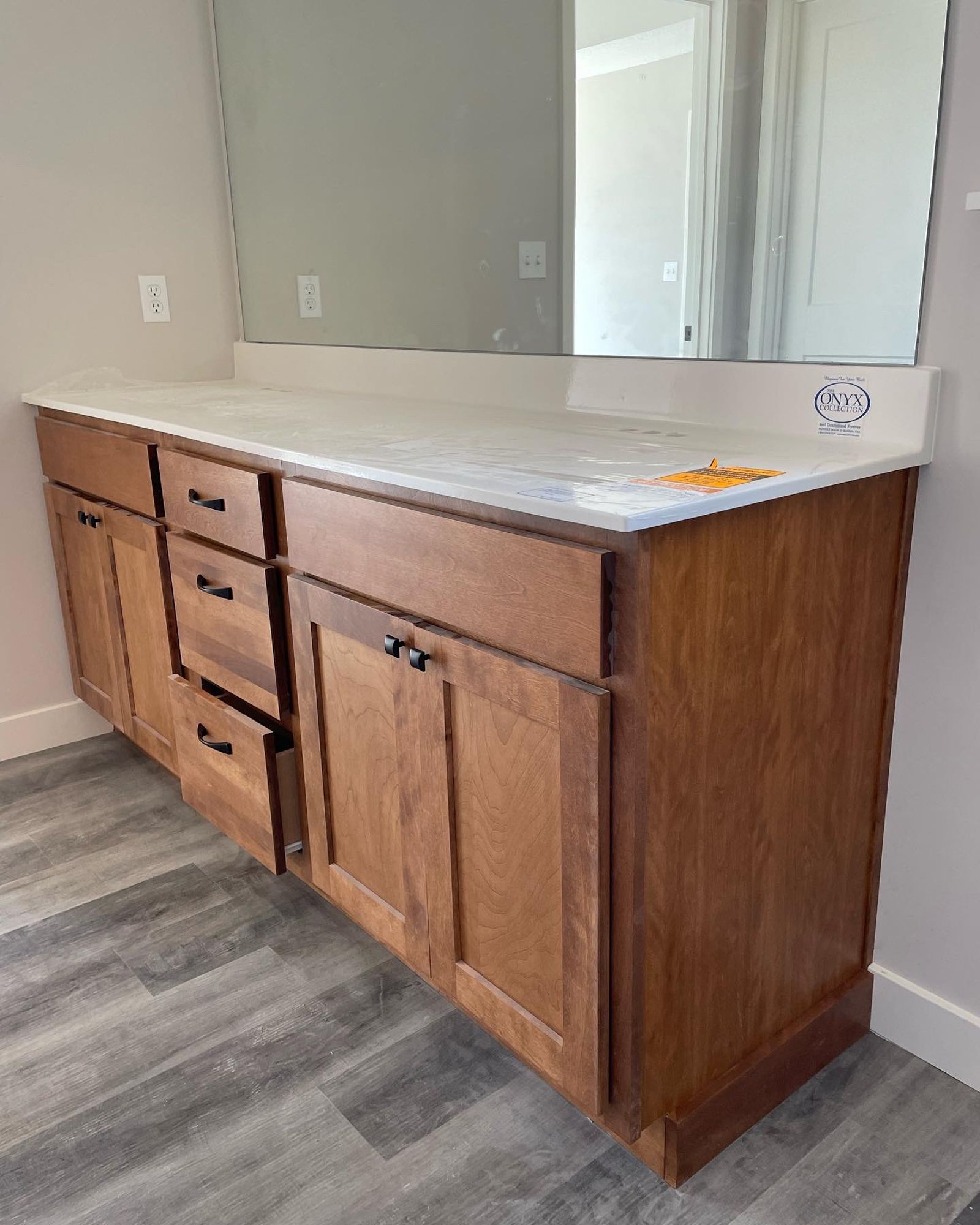 Wooden bathroom vanity with white countertop and mirror.