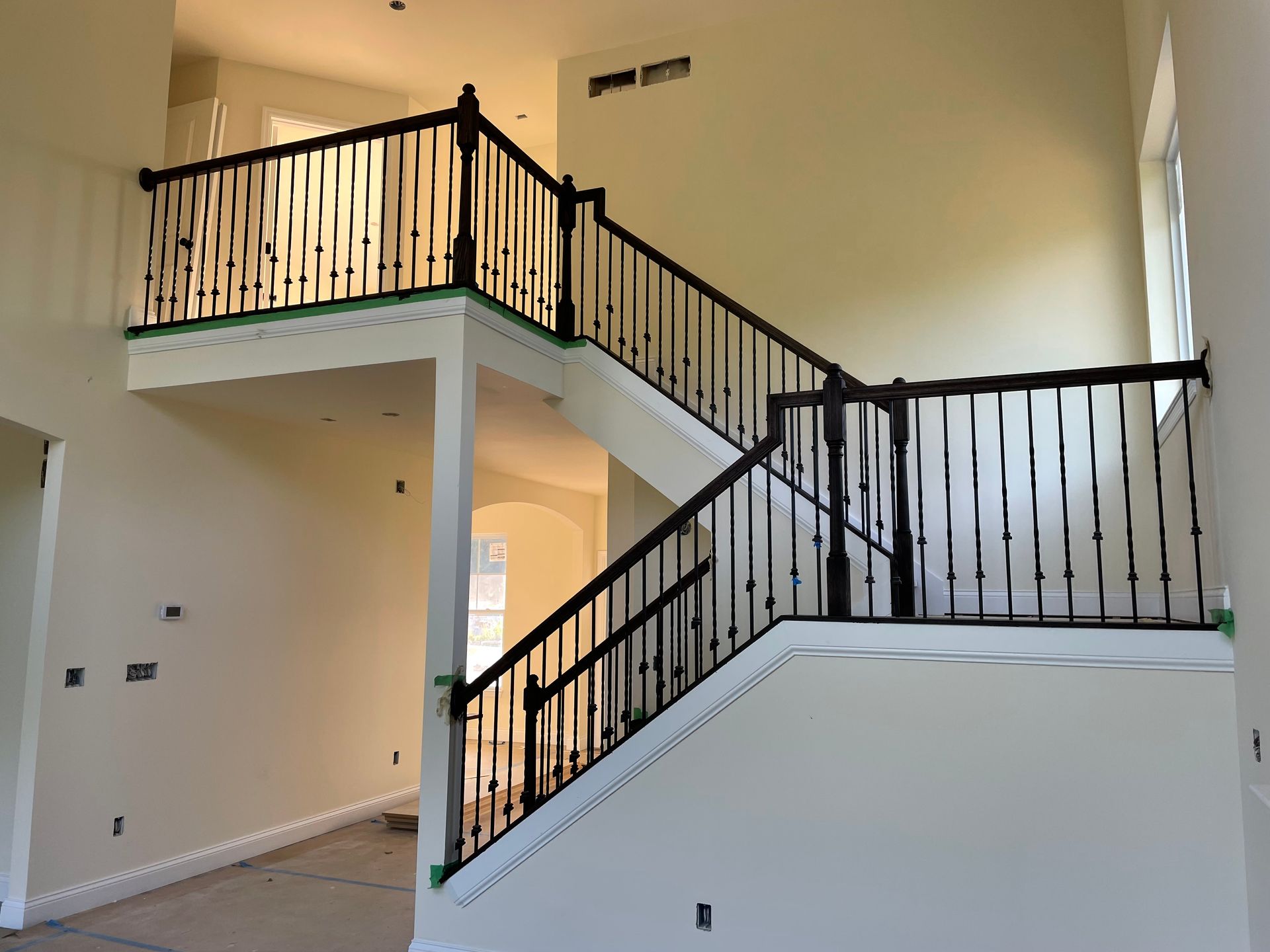 Two-story interior with a dark-railed staircase against beige walls.