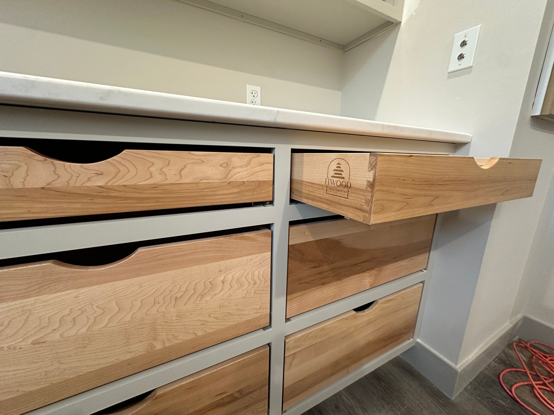 Wooden drawers in a white cabinet, one drawer open.