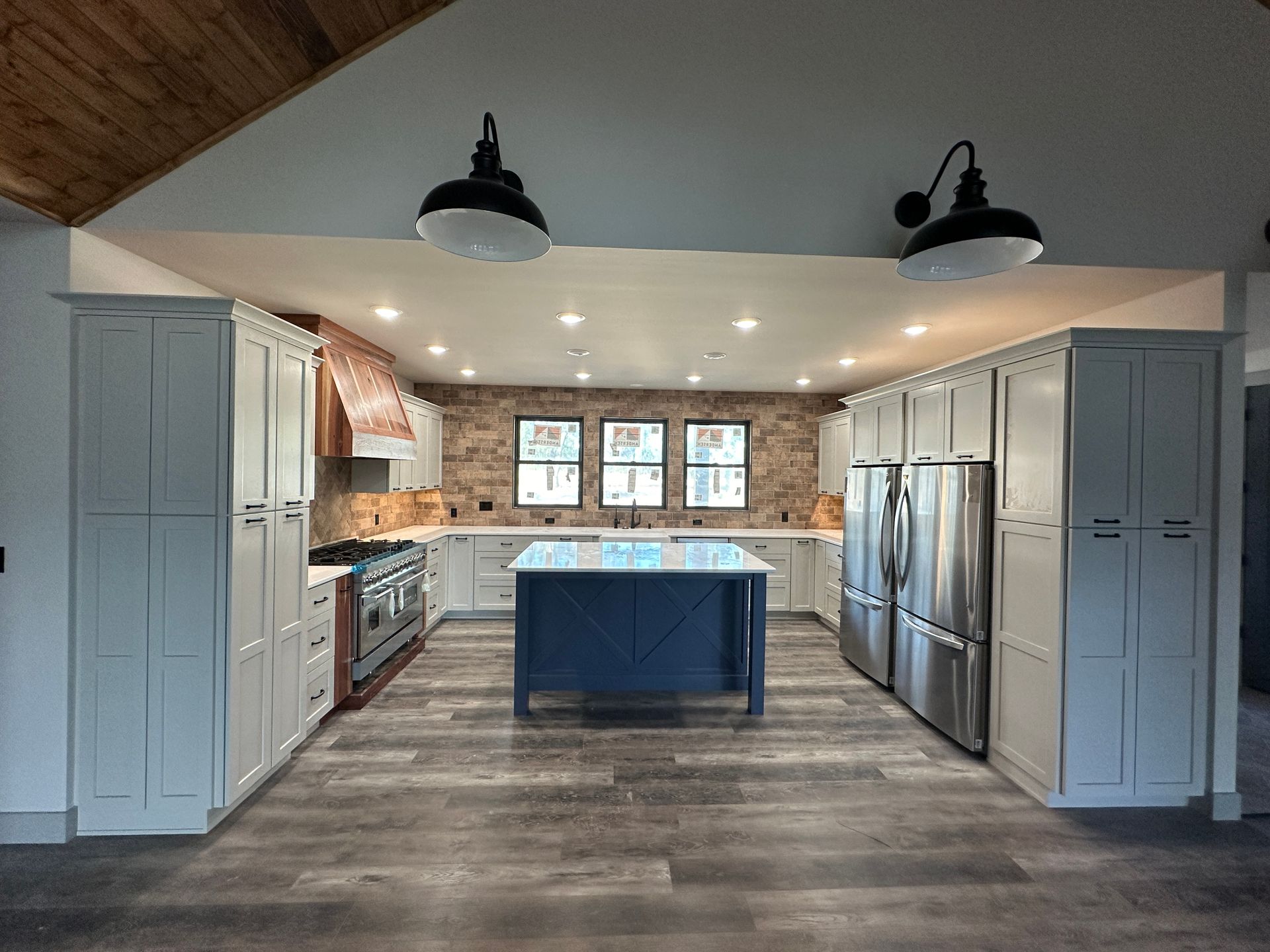 Spacious modern kitchen with blue island, stainless steel appliances, and white cabinets.