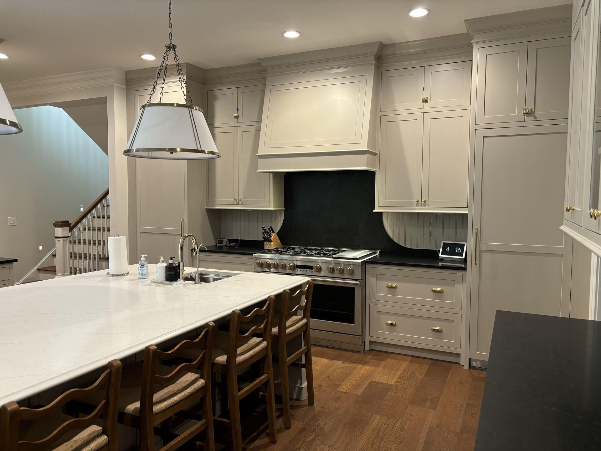 Kitchen with white cabinets, large island, stainless steel appliances, and wooden floors.