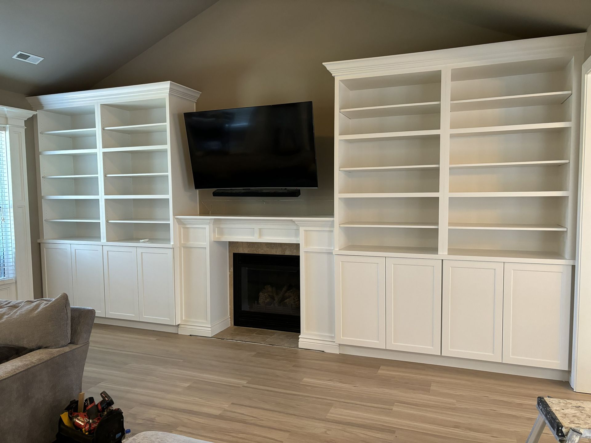 White built-in bookshelves frame a fireplace and mounted TV in a living room.