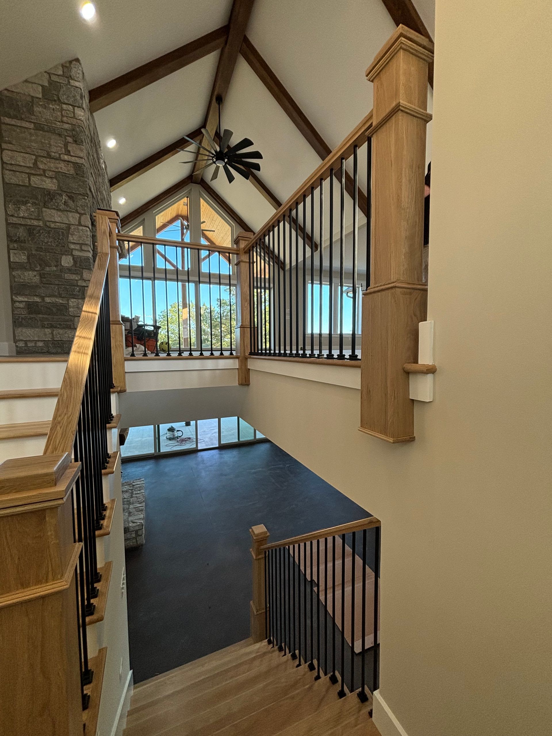 Interior view of a house with a staircase, railing, and vaulted ceiling with exposed beams.