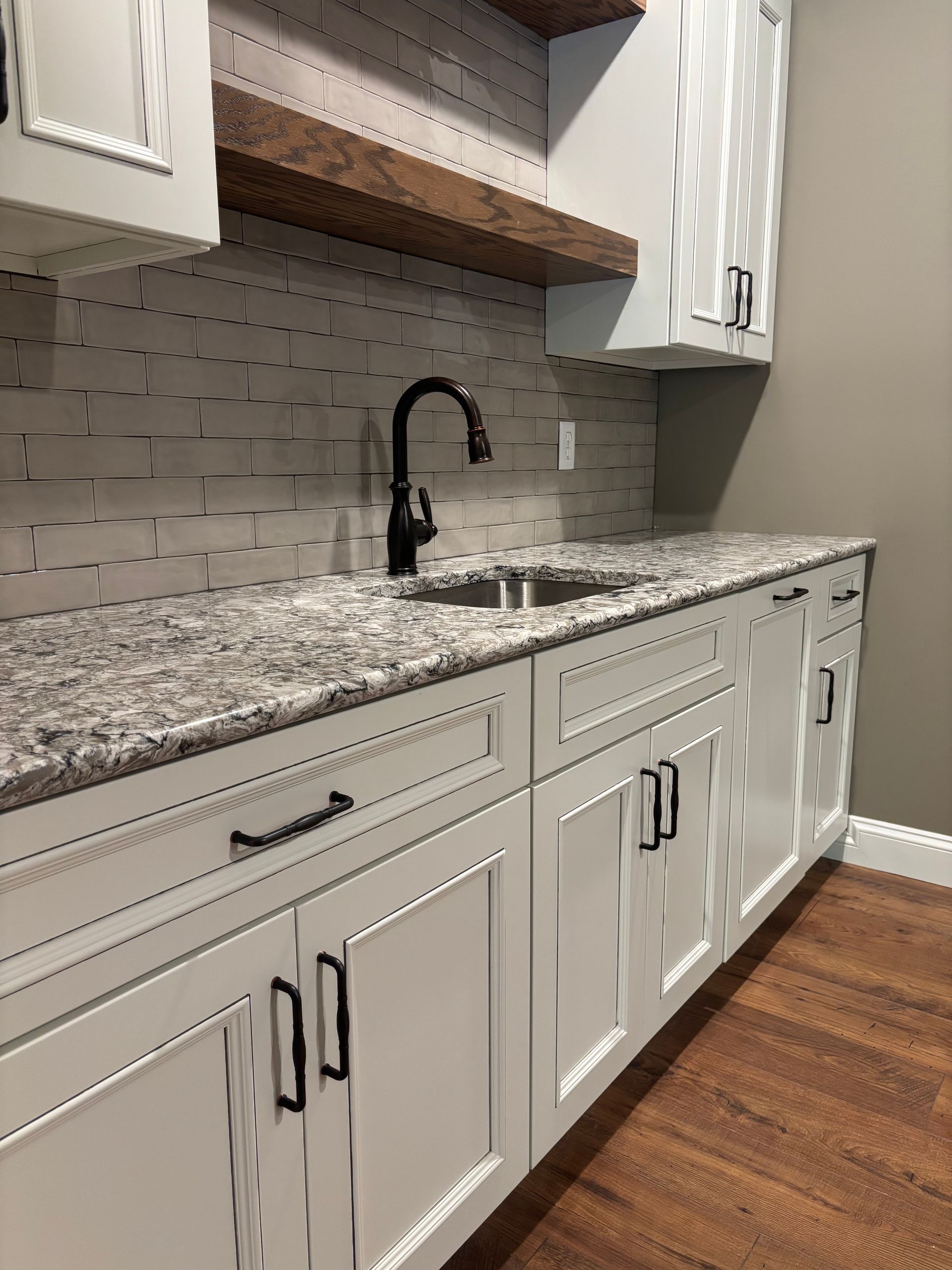 White cabinets with granite countertop and black faucet in a kitchen.