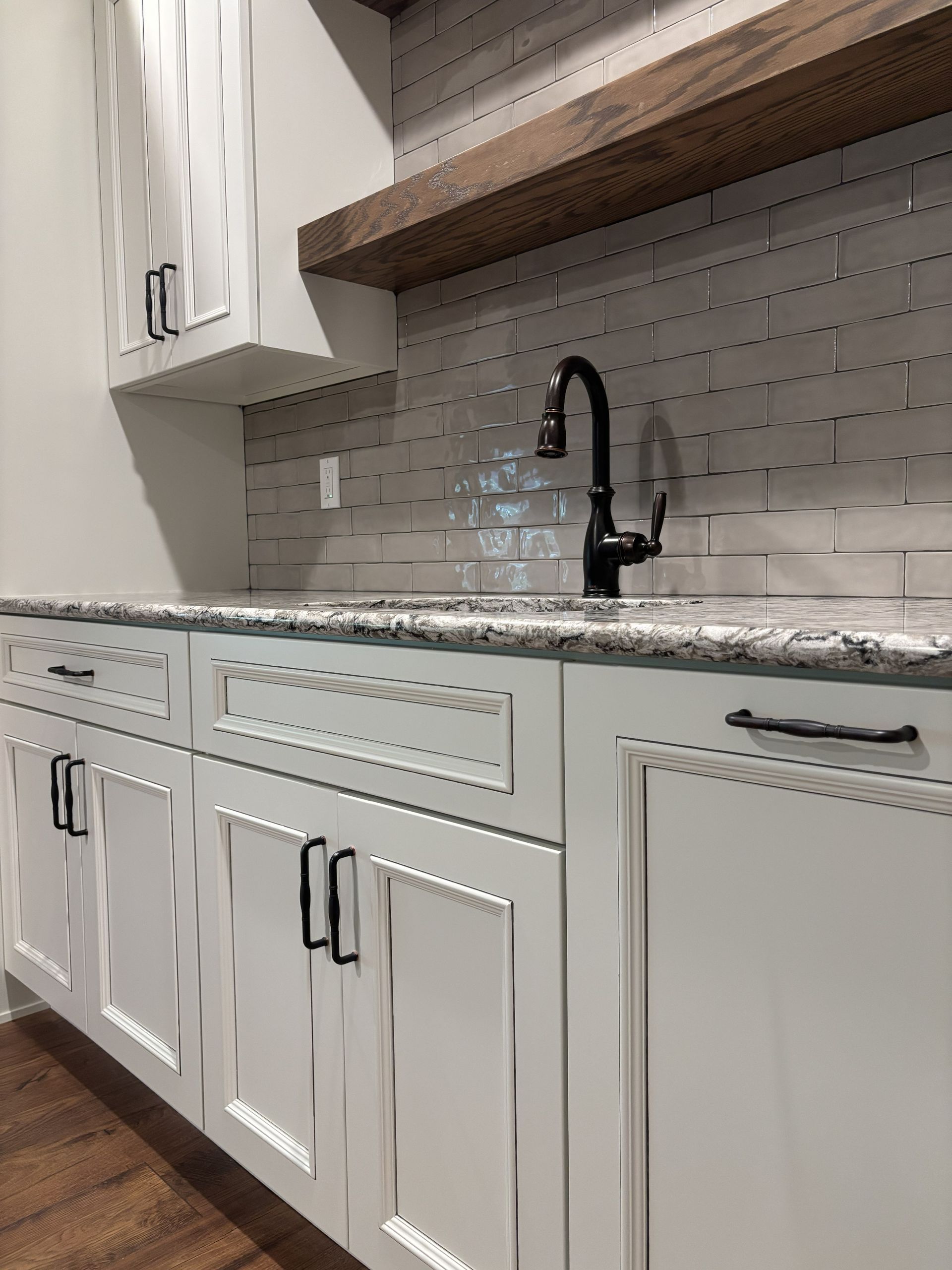White cabinets, a granite countertop, and a black faucet in a kitchen setting.