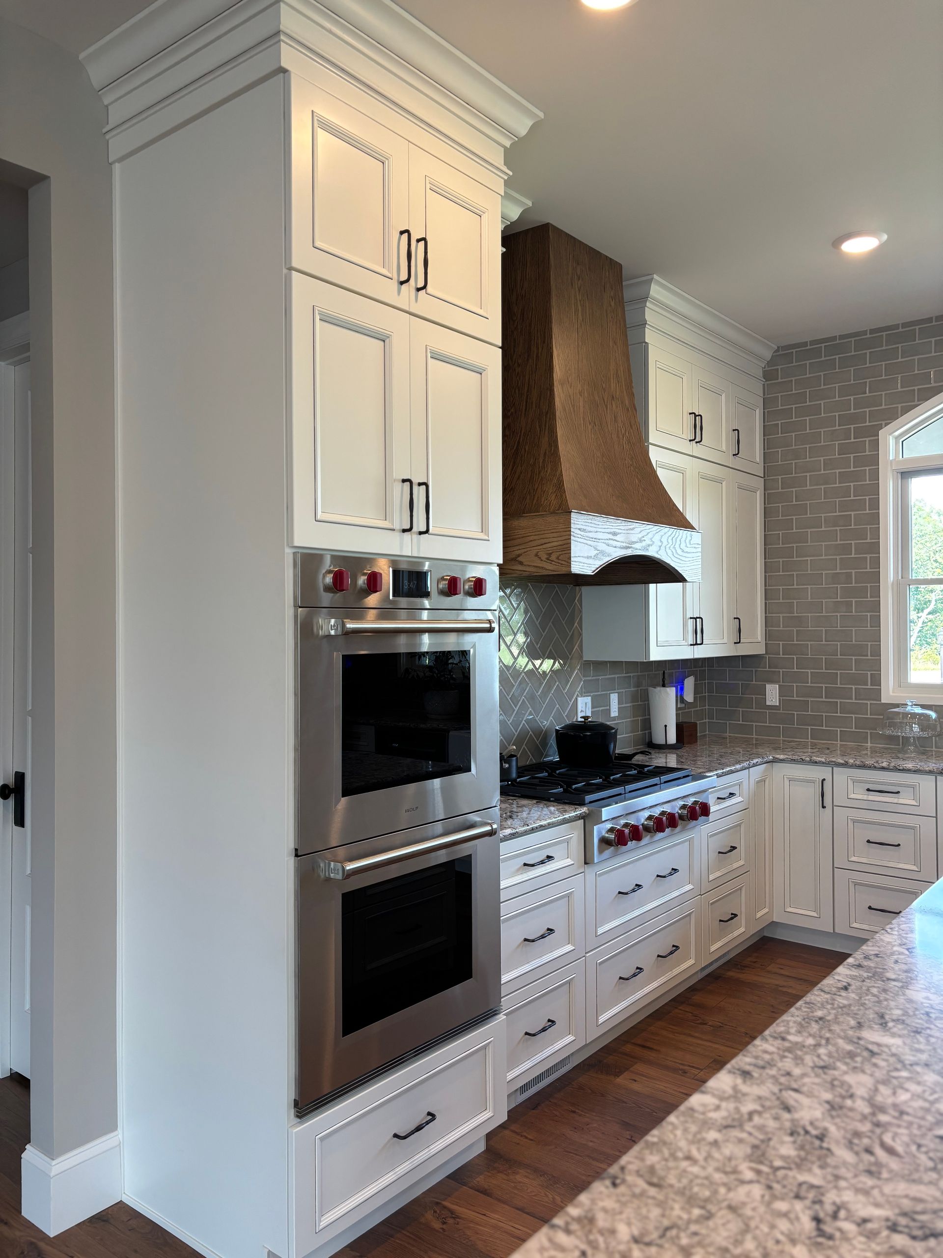 White kitchen cabinets with stainless steel oven, copper range hood, and tile backsplash.