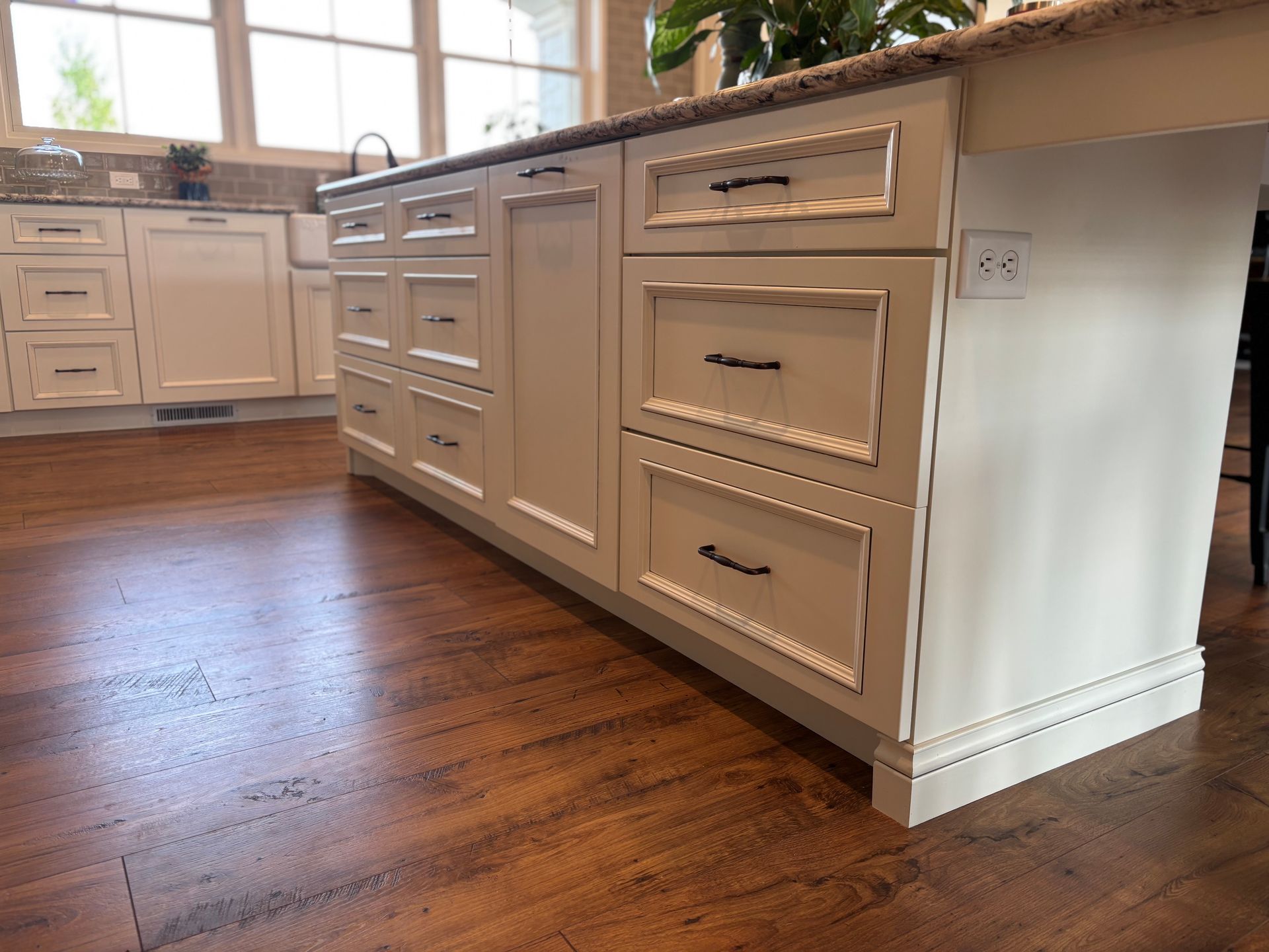Kitchen island with cream cabinets, dark hardware, and a wood floor.