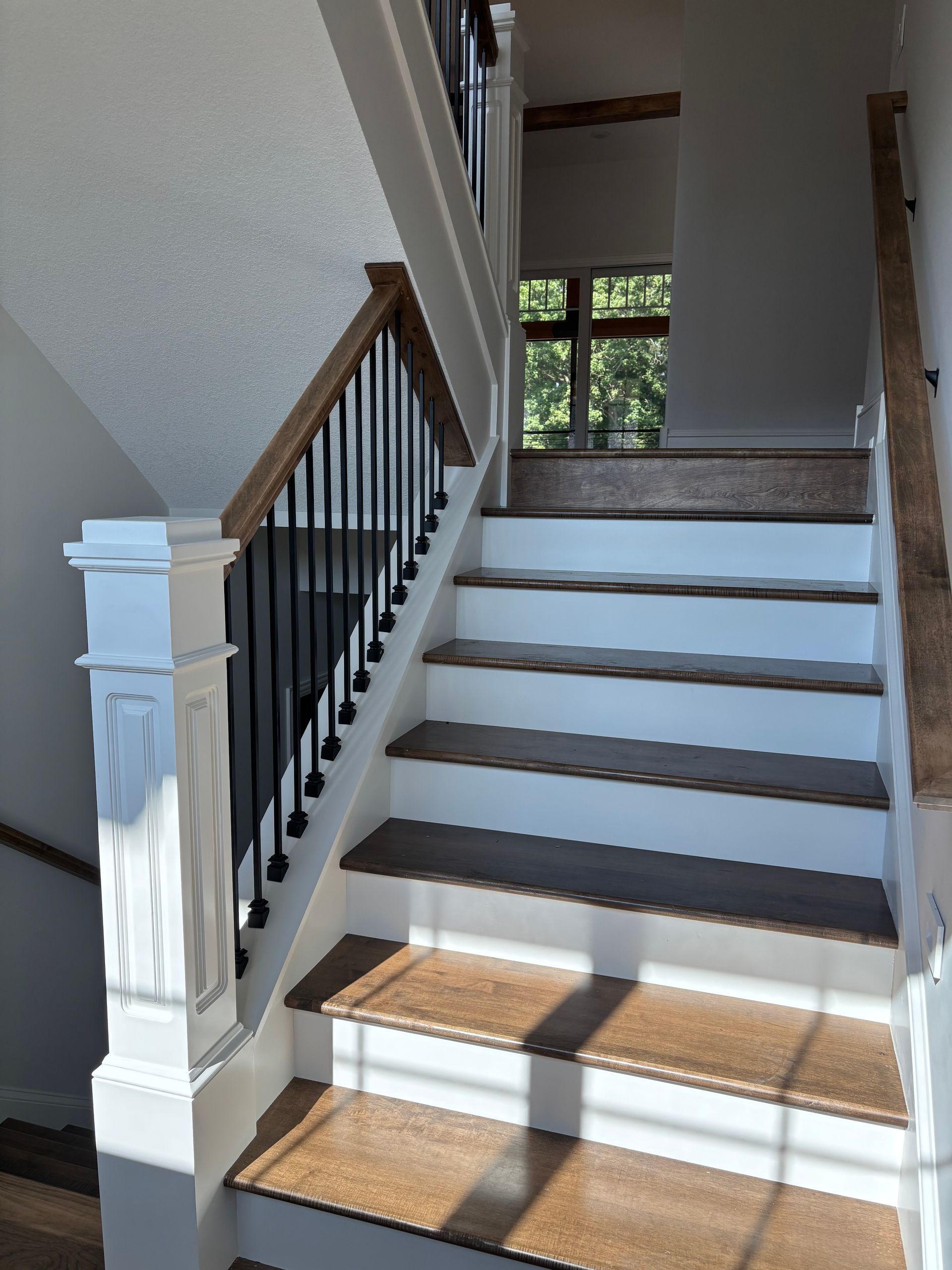 Staircase with wooden steps and railing, black iron spindles, white trim.