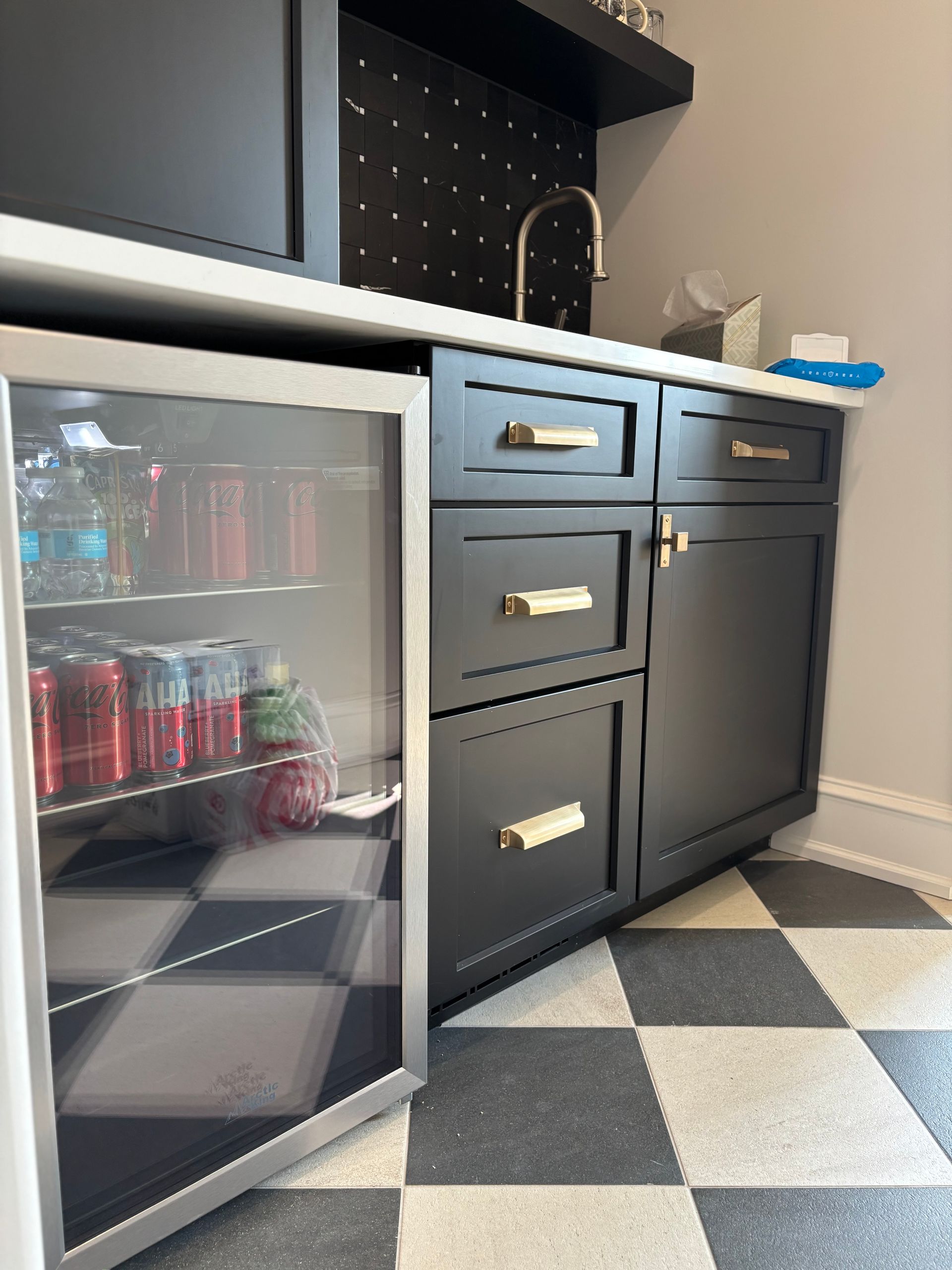 Black cabinet with cooler, checkered floor, and countertop with sink.