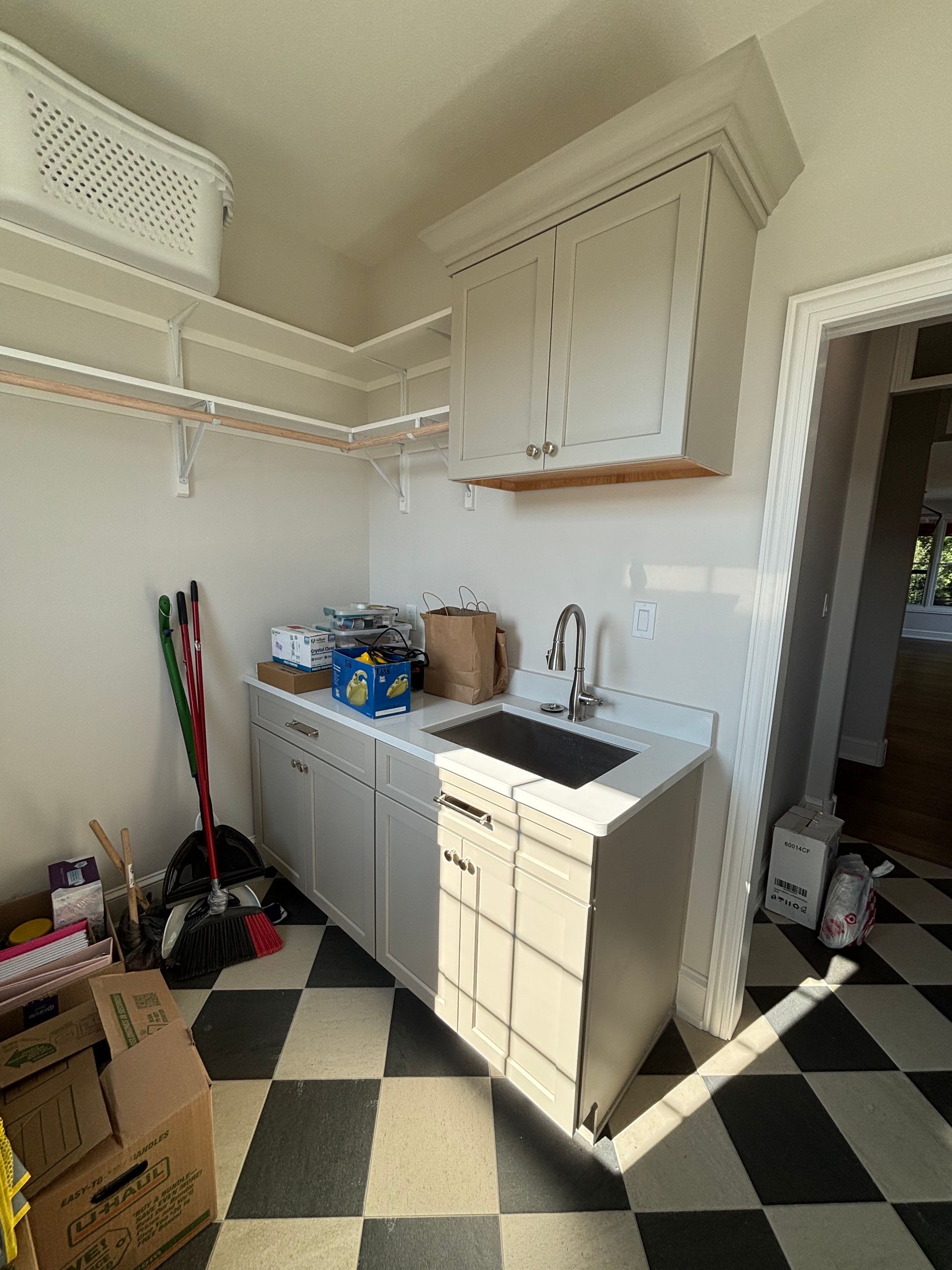 Laundry room with white cabinets, sink, and black and white checkered floor.