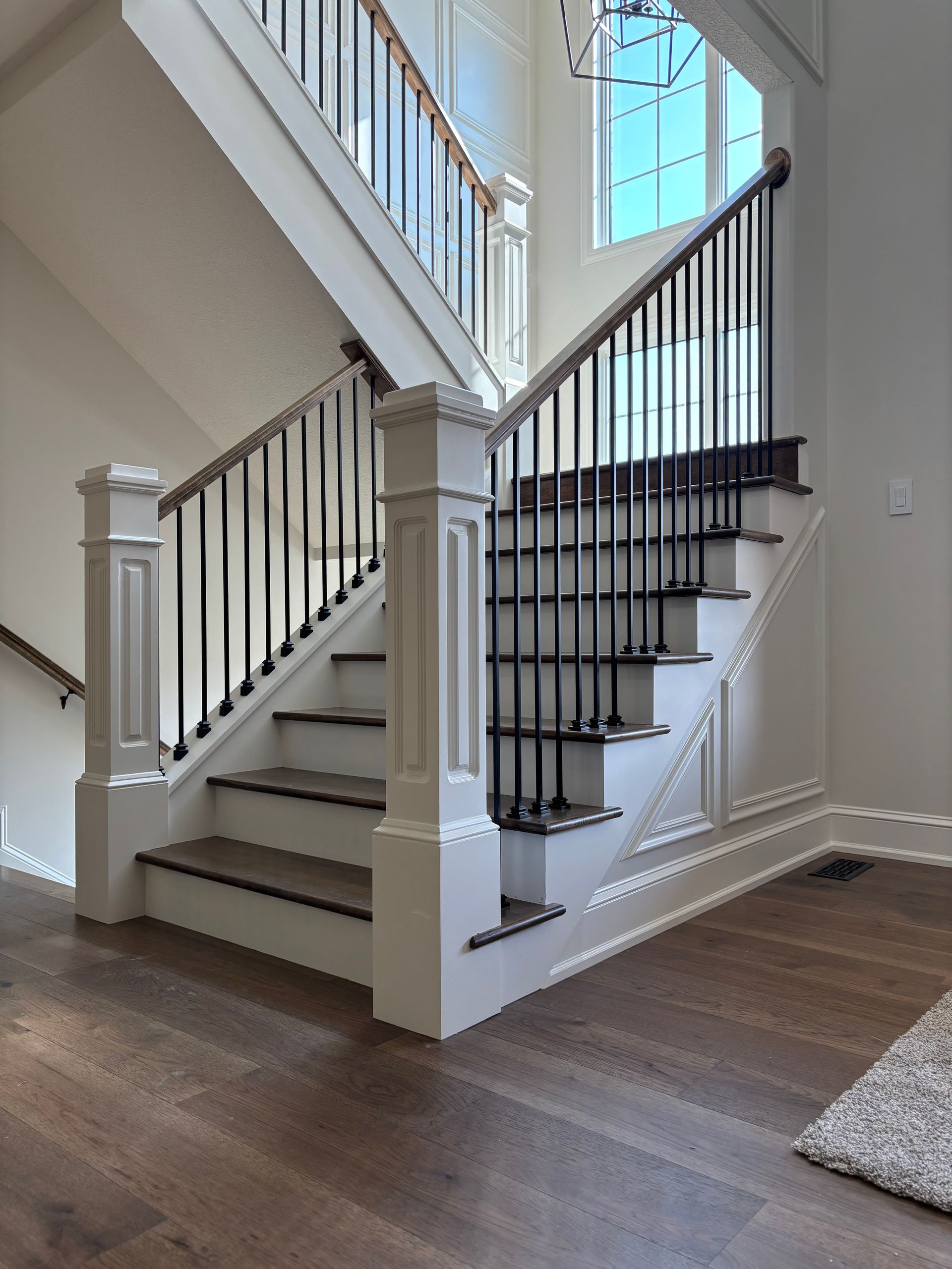 A wooden staircase with dark railings and white trim in a bright, modern home.