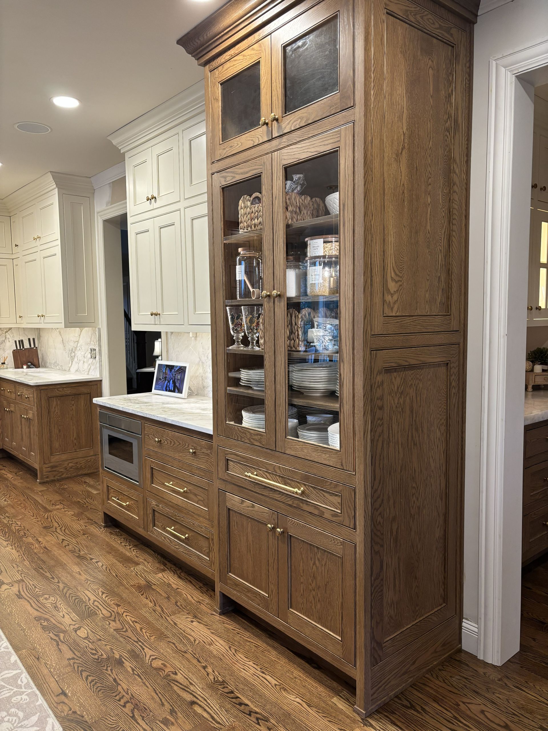 Wooden kitchen cabinets with glass doors, and light countertops. Hardwood floors.