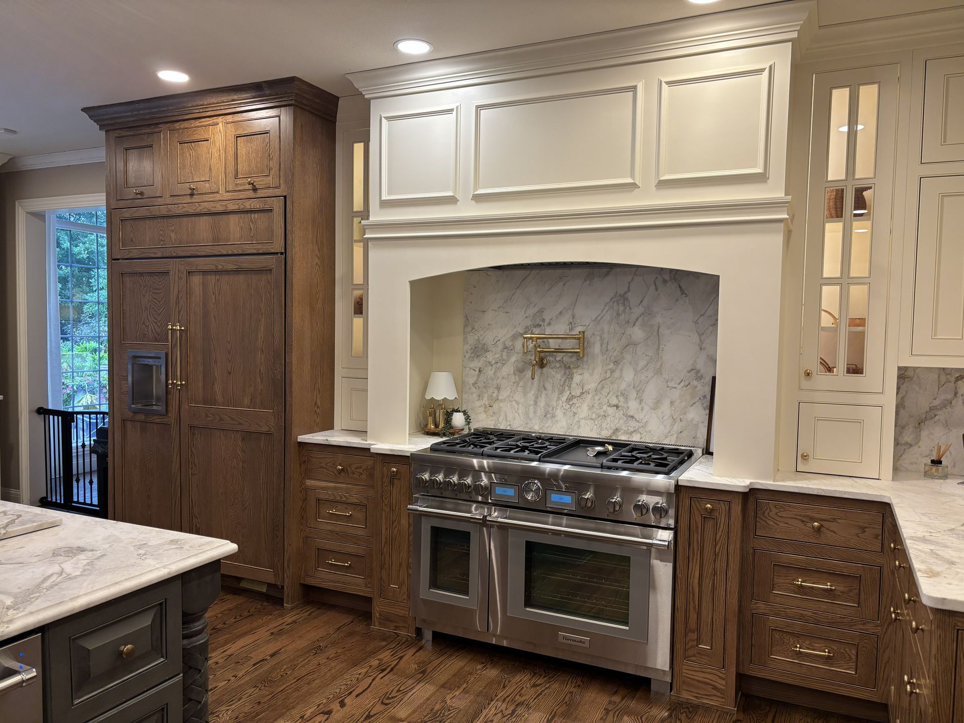 Kitchen with brown and white cabinetry, stainless steel range, and marble backsplash.