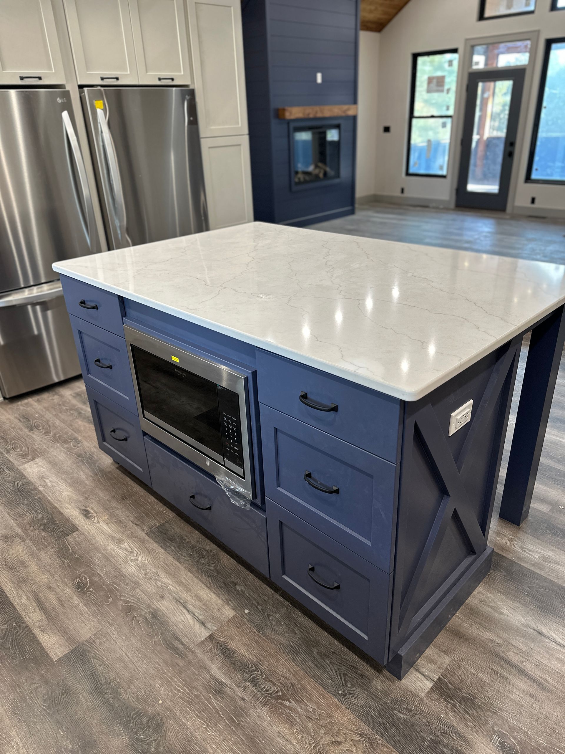 Blue kitchen island with microwave, drawers, and white countertop. Modern kitchen setting.