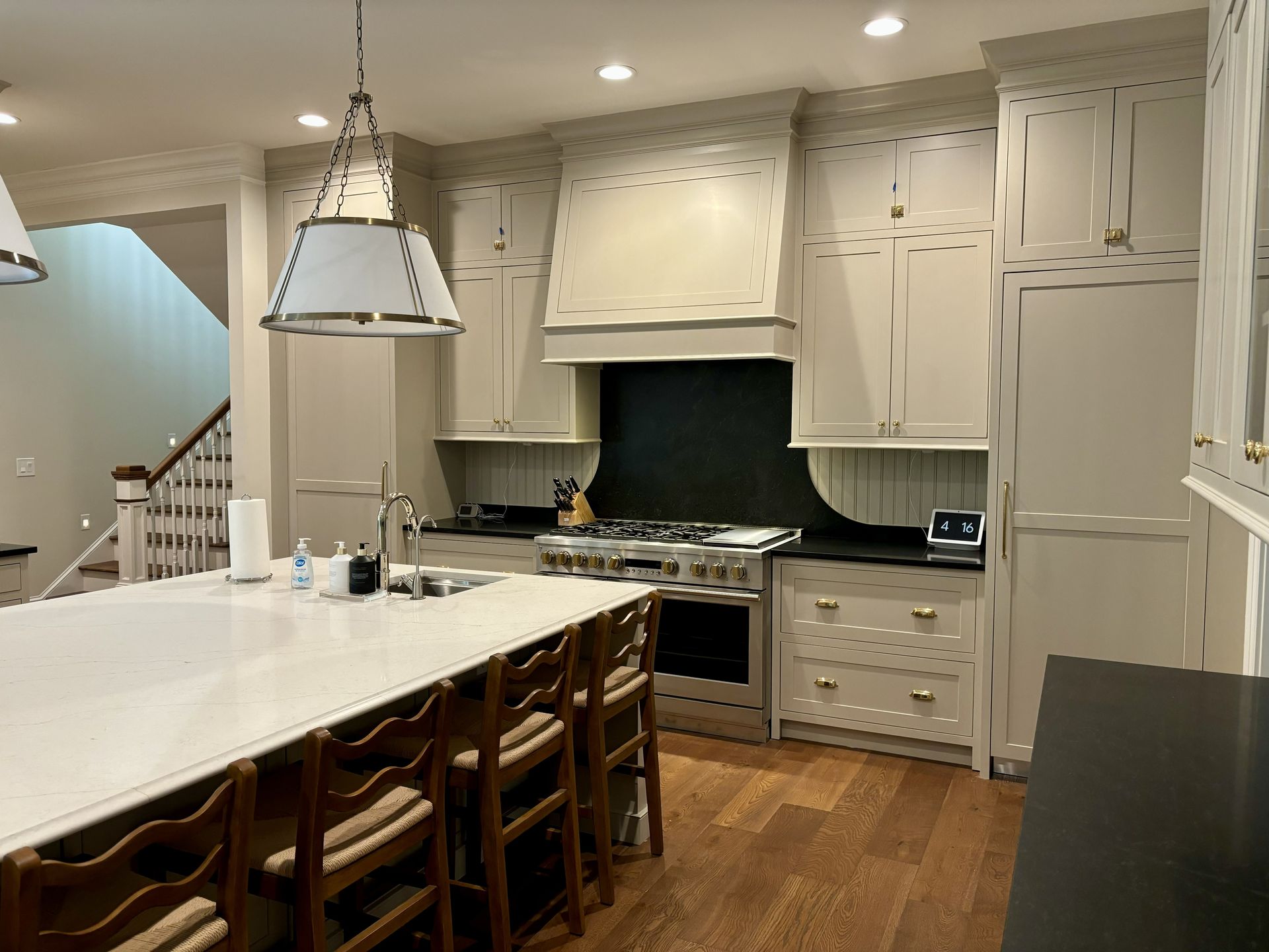 Kitchen with island, wood floors, light-colored cabinets, stainless steel appliances, and hanging light fixtures.