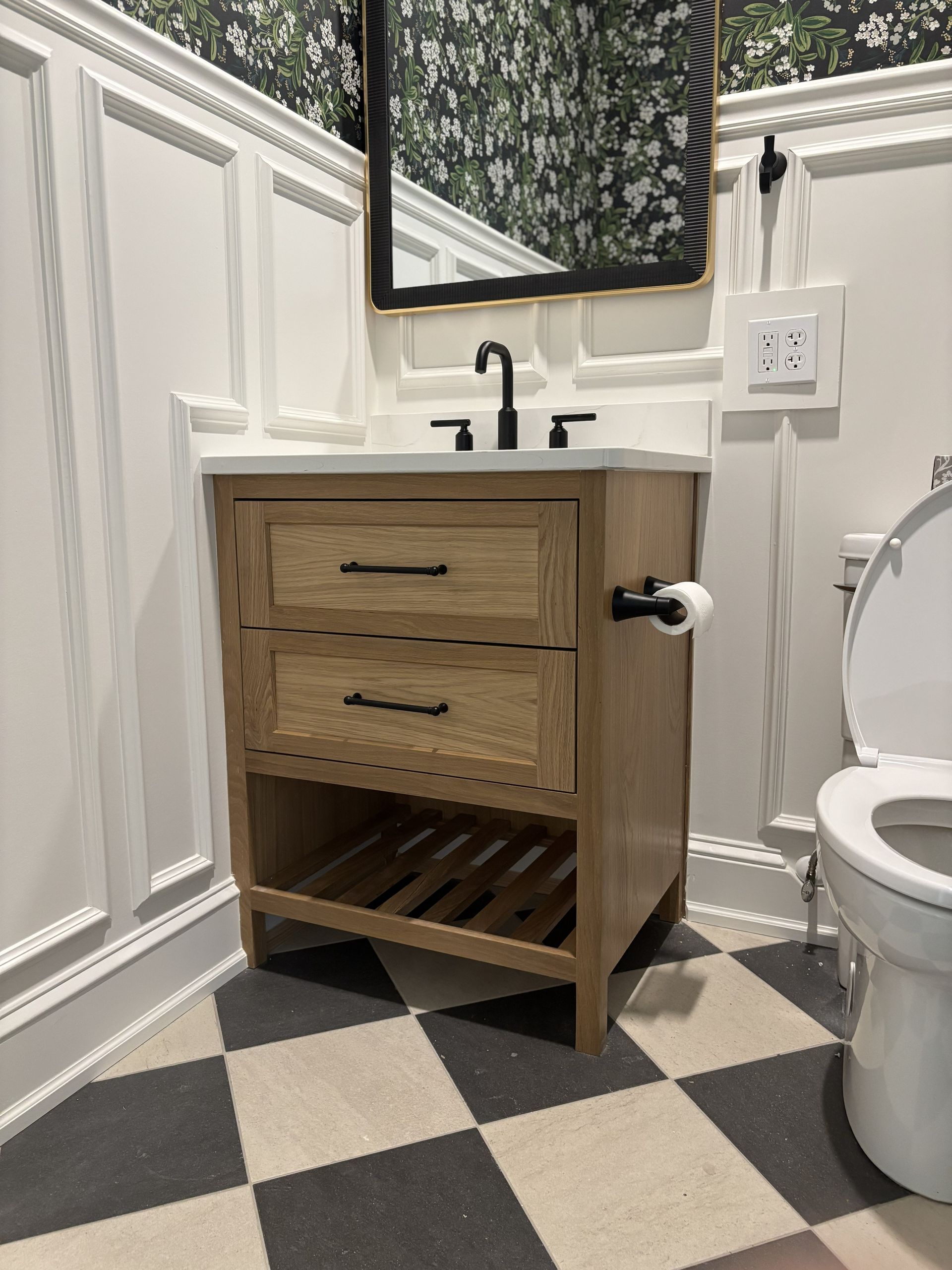 Bathroom vanity with wooden cabinet, black hardware, and checkered floor.