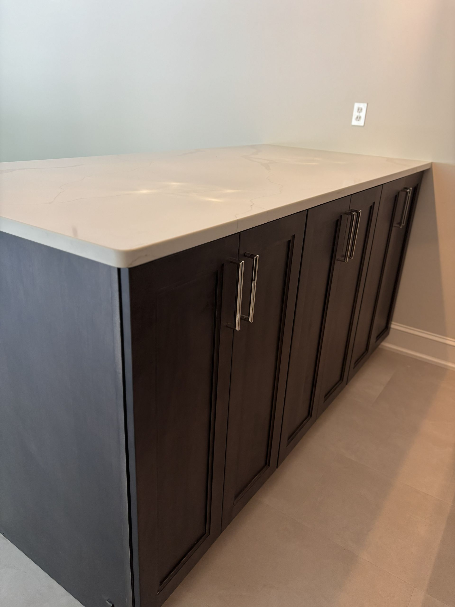 Dark brown kitchen island with a white countertop and silver hardware.