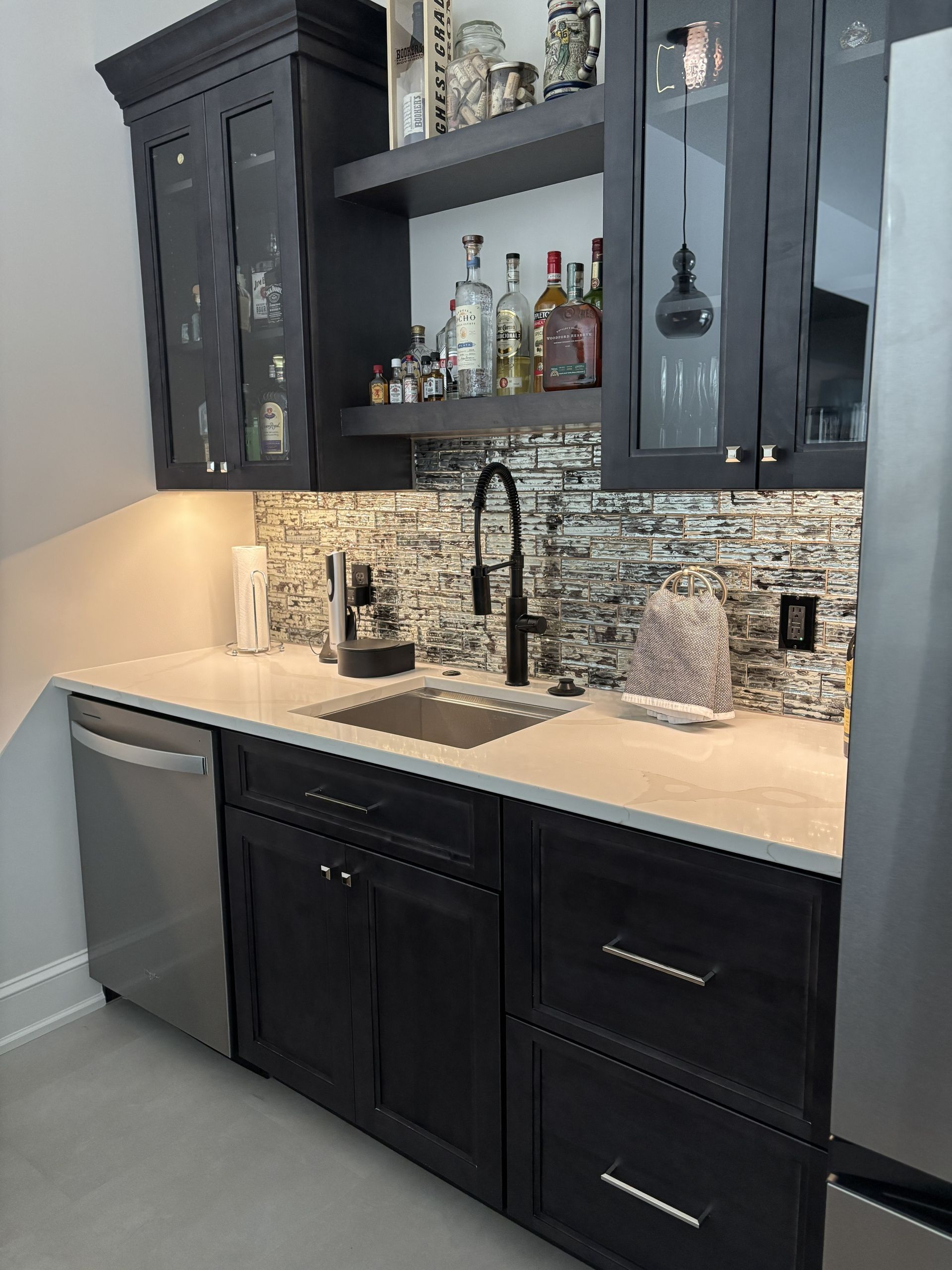 Dark gray wet bar with a sink, liquor shelves, and a dishwasher.